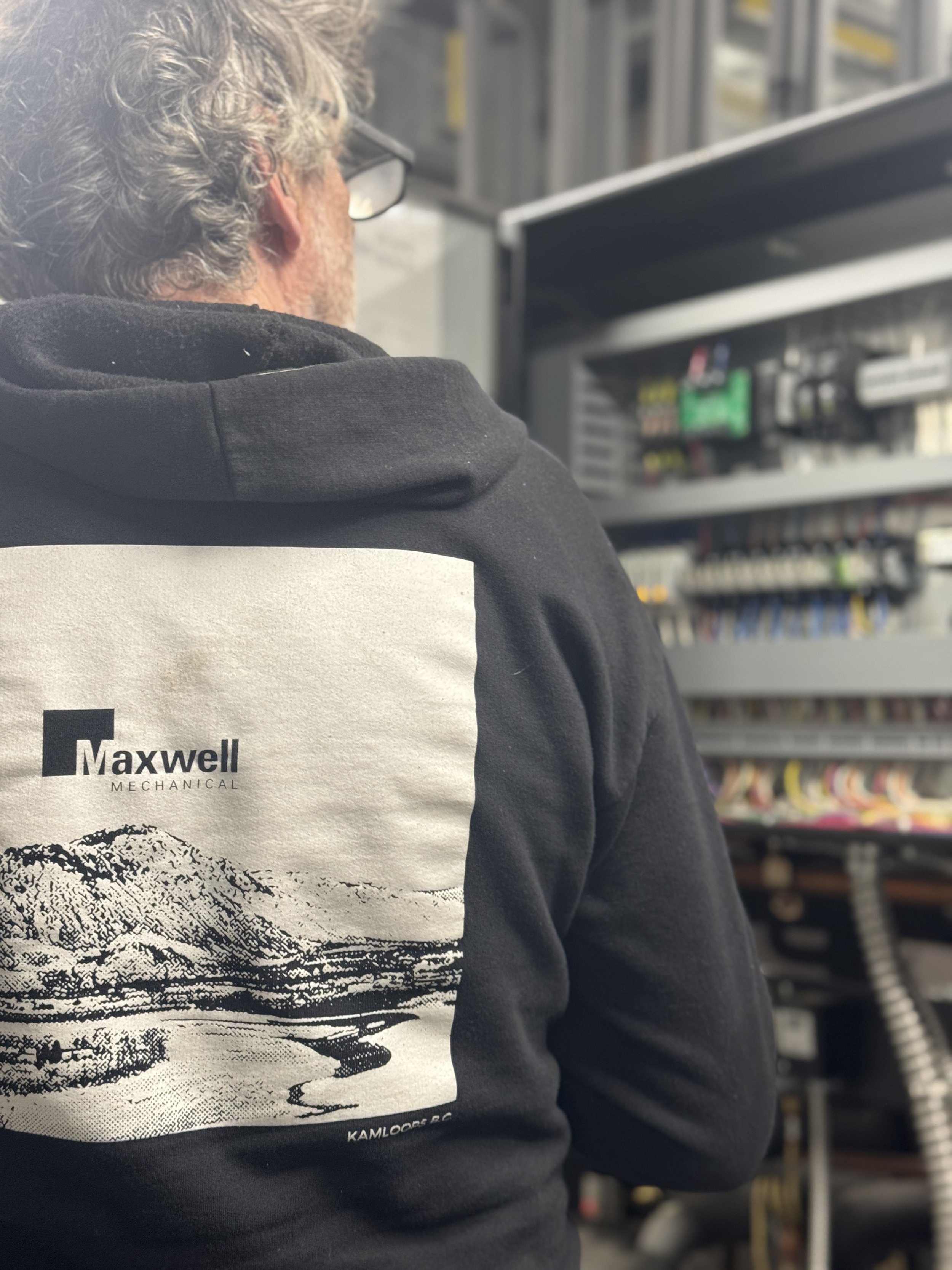 Maxwell Mechanical team member inspecting an electrical control panel for a commercial mechanical system.
