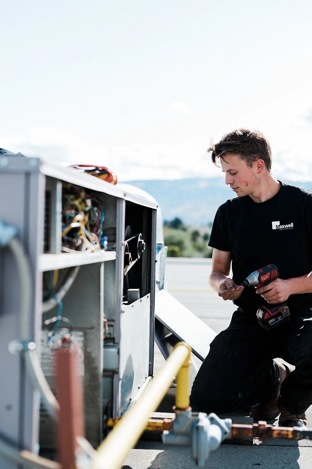 Maxwell Mechanical technician working on rooftop HVAC equipment with tools during a commercial service call in Kamloops.