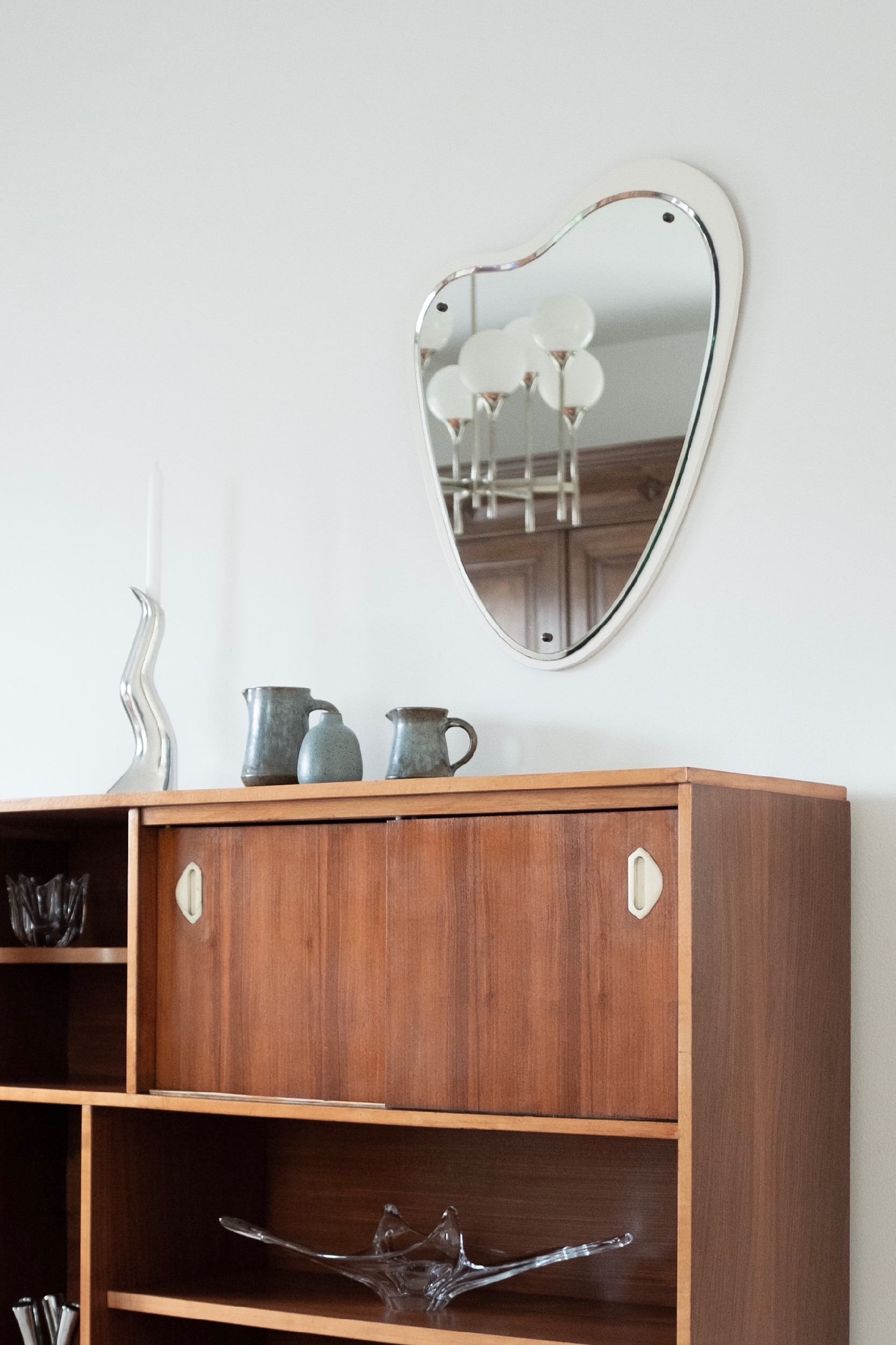 Anna Efverlund candleholder and blue ceramic vases on restored wooden sideboard in with organic shape mirror.