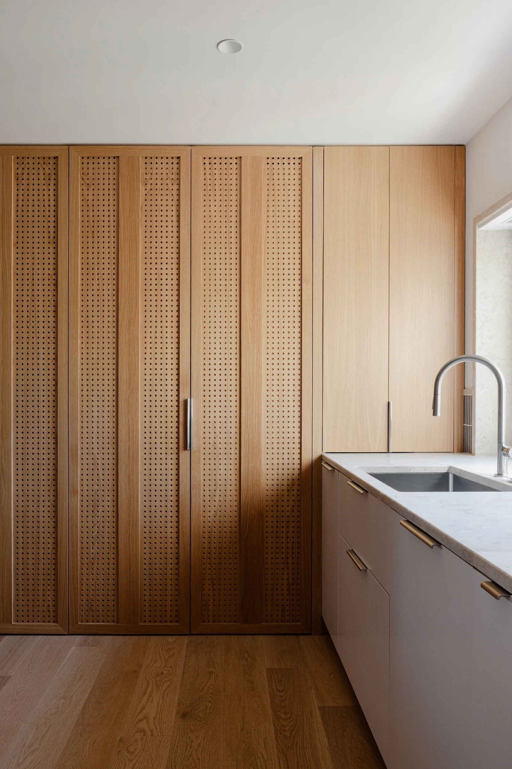Lola Cwikowski Studio Cascais Residence project with custom Lioz kitchen countertop with integrated sink; Hansgrohe Talis M54 faucet; custom perforated oak laundry cabinet doors; oak wall cabinets; Fenesteves engineered oak floor.