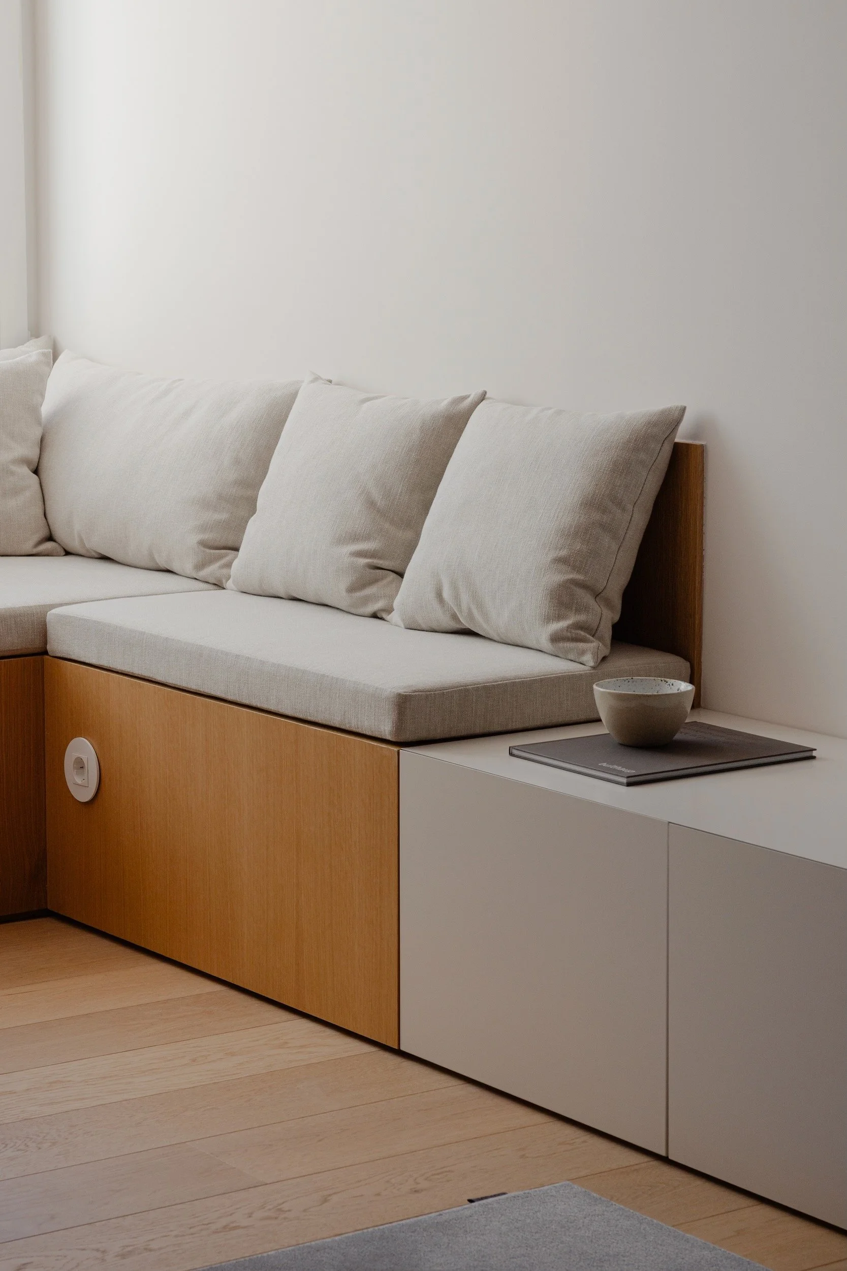 Lola Cwikowski Studio Cascais Residence project with detail of custom oak bench with Maria Menino cushions in Lauritzon Aqua; custom media unit; ceramic bowl on book; Efapel Siza socket; Fenesteves engineered oak floor, CutCut Praia rug.