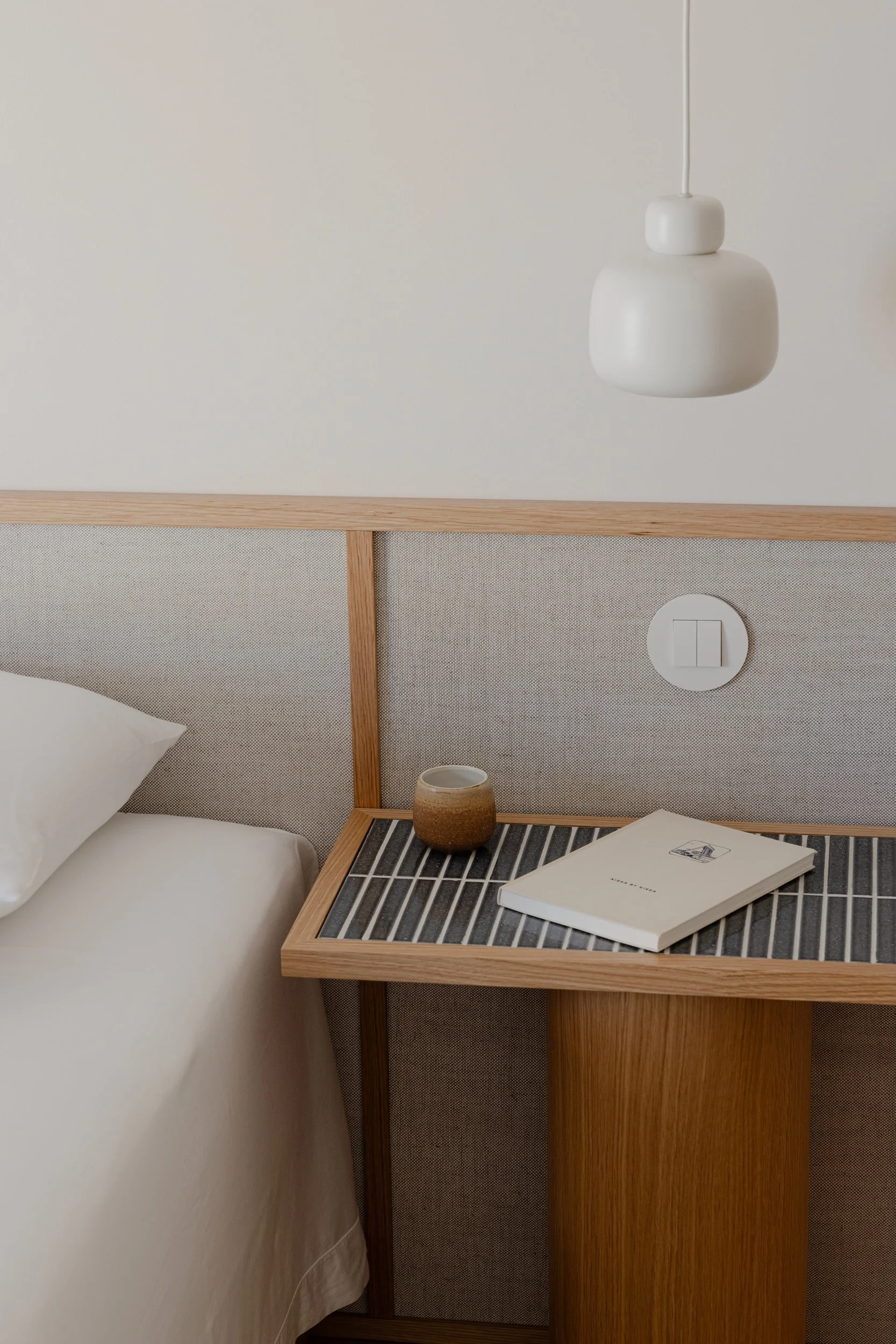 Lola Cwikowski Studio Cascais Residence project with detail of custom Somma Carpintaria oak & linen headboard; nightstand with Marokk Kayo Tokyo tile top; Woud Stone pendant; Kissa by Kissa, Craig Mod.