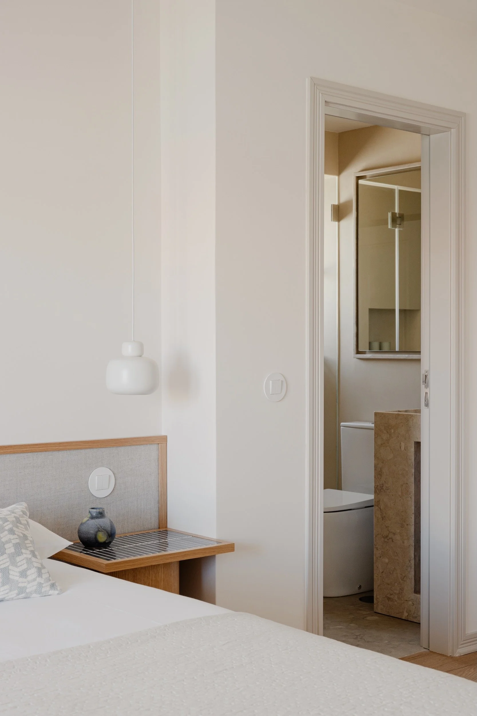 Lola Cwikowski Studio Cascais Residence project with custom oak & linen headboard; nightstand with Marokk Kayo Tokyo tile top; Woud Stone pendant; vintage ceramic vase; en suite with Lioz pedestal sink.