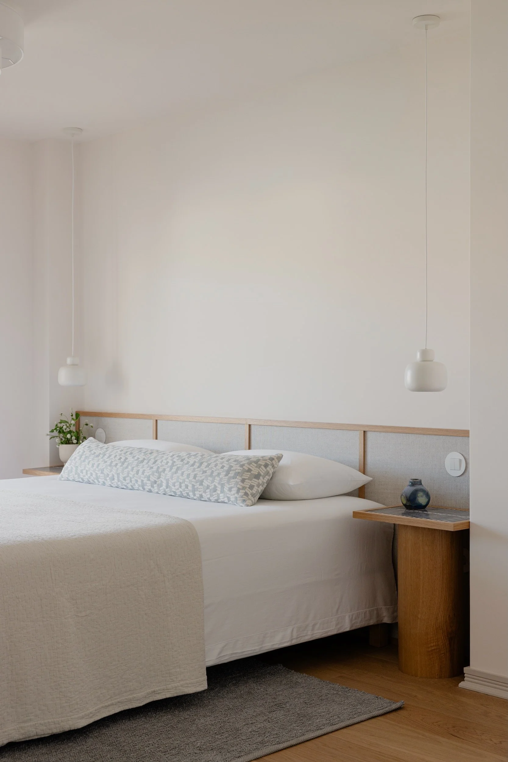 Lola Cwikowski Studio Cascais Residence project with custom Somma Carpintaria oak & linen headboard with tiled nightstands; Woud Stone pendants; Seeds Concept Wrinkle bedspread; Teia Atelier handwoven rug.