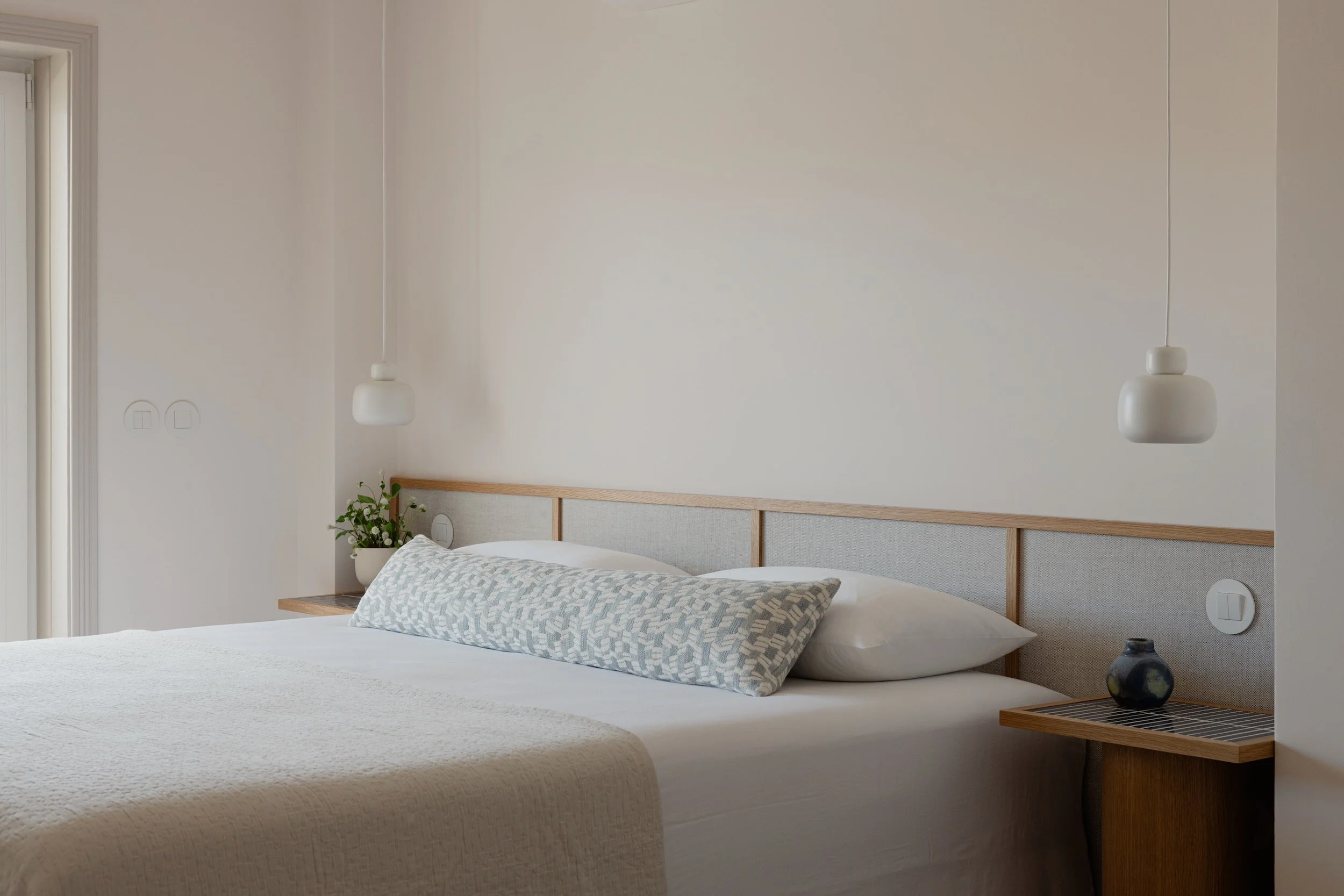 Lola Cwikowski Studio Cascais Residence project with custom Somma Carpintaria oak & linen headboard with integrated nightstands in Marokk Kayo Tokyo tile; Woud Stone pendants; Larsen Tomas pillow; vintage vase.