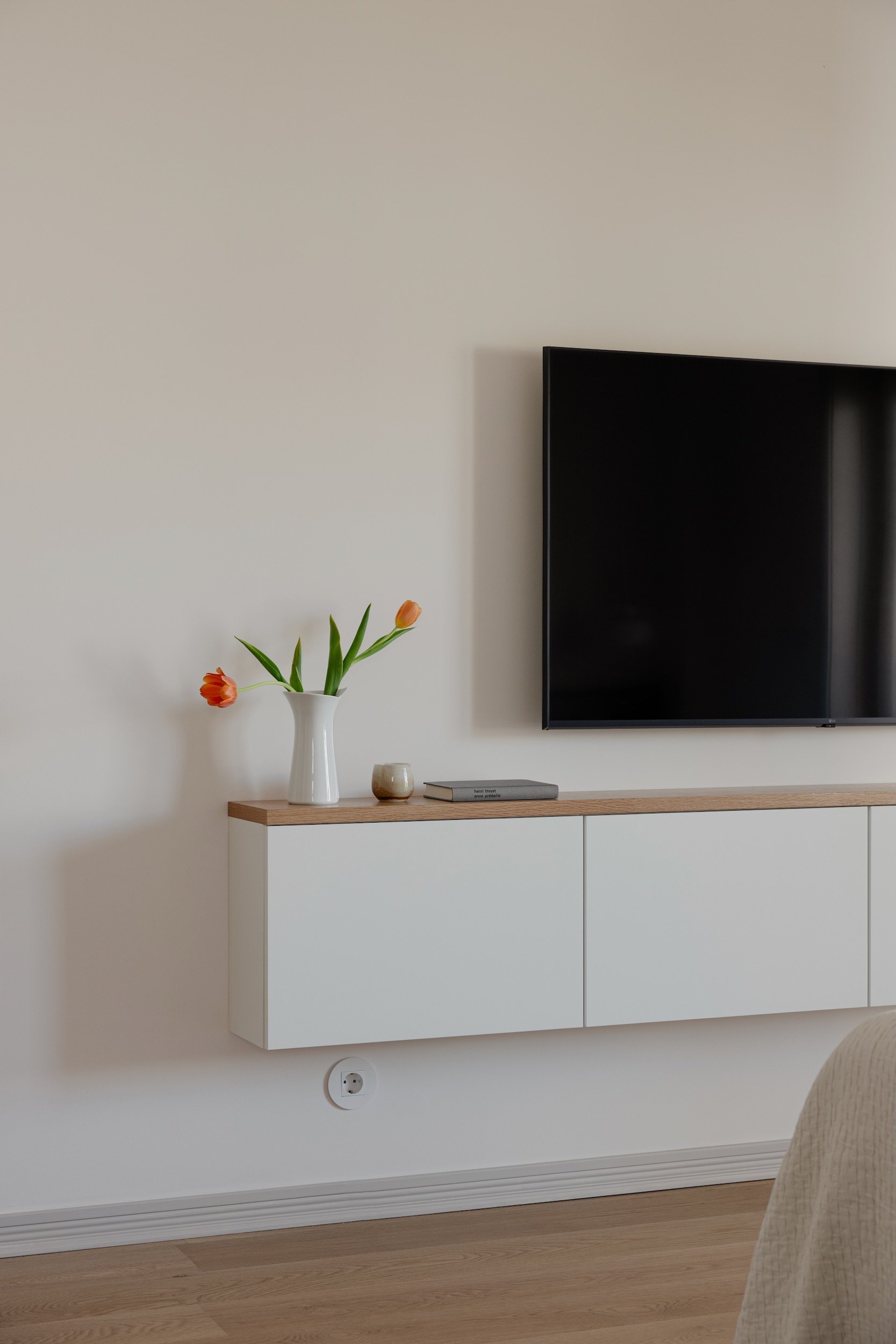Lola Cwikowski Studio Cascais Residence project with custom oak top panel on IKEA Bestå console; LG TV; Apricots, Pears & Peaches, Florin Gheorghiu; ceramic pitcher with tulips.