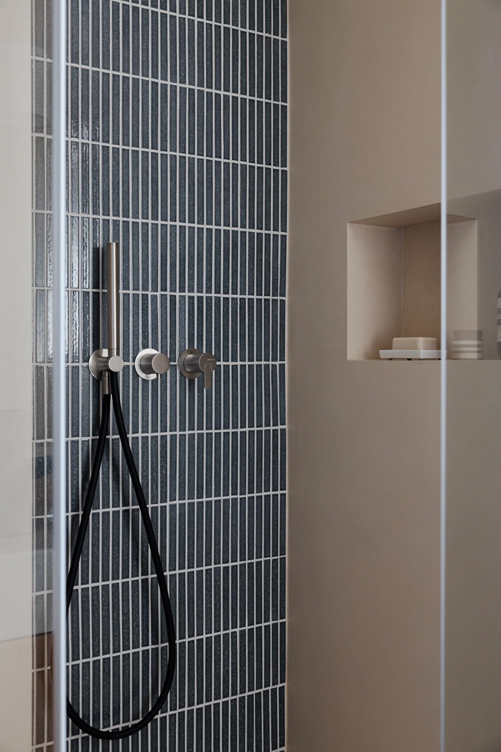 Lola Cwikowski Studio Cascais Residence project with close-up of Bruma X-Alpha shower controls & handshower; Marokk Kayo Tokyo tile; microcement wall with Brilumen LED niche; glass shower screen.