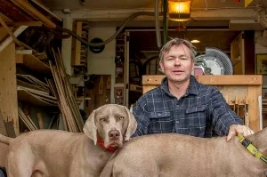 Ted Havens, owner of Portlandia Remodeling & Home Maintenance, in his workshop with his dog