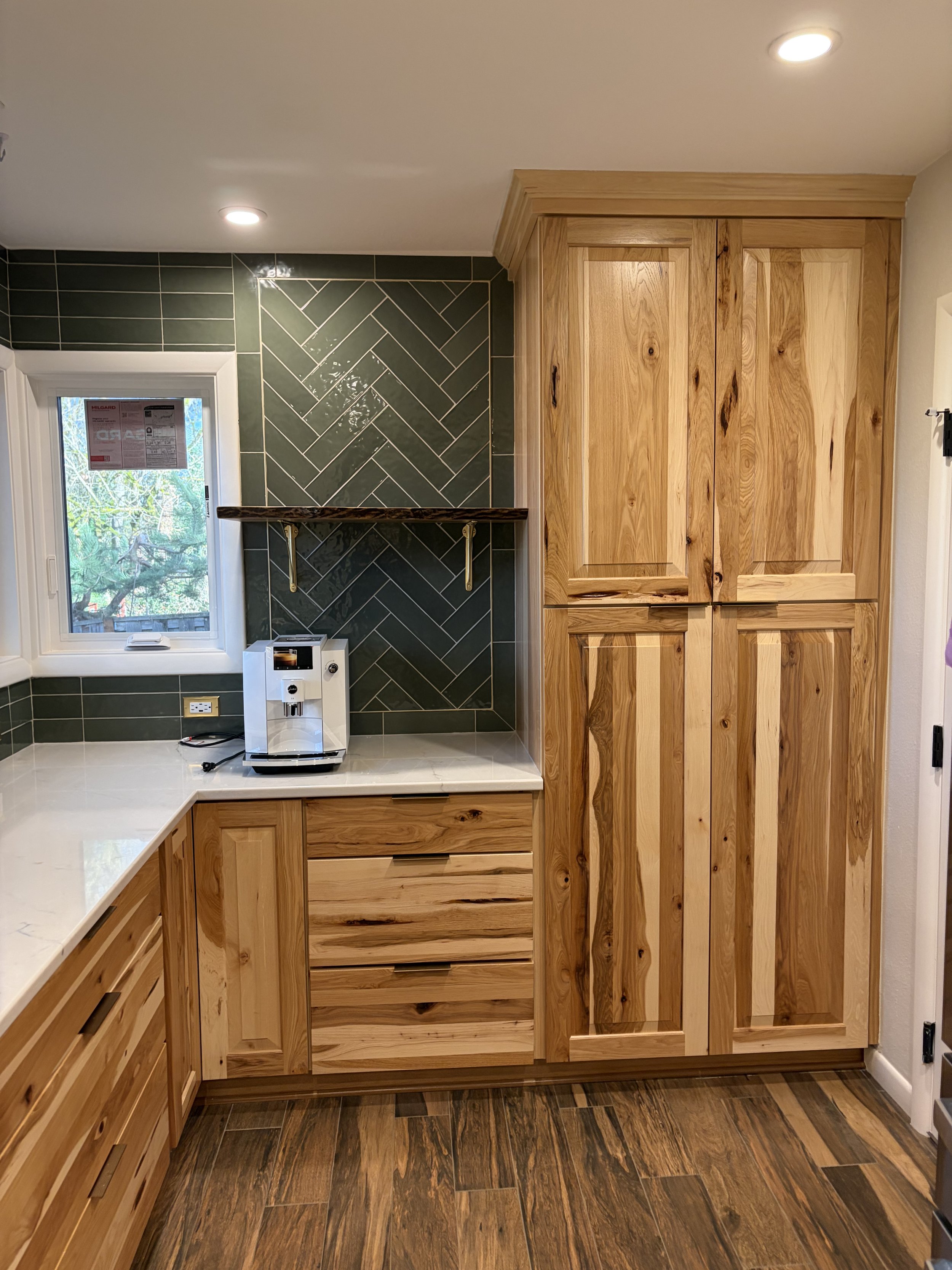 Green herringbone tile kitchen backsplash installed with custom wood cabinetry and quartz countertops in a Portland kitchen remodel.