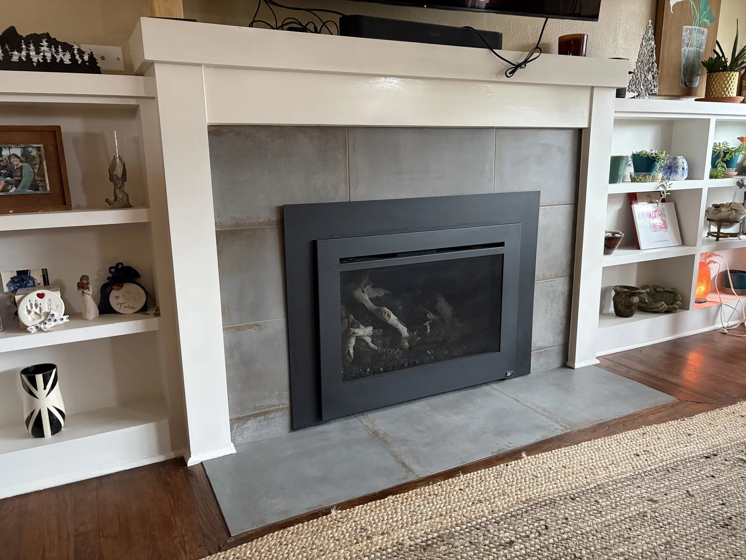 Custom fireplace tile surround with porcelain tile hearth, painted mantel, and built-in shelving in a Portland home remodel.