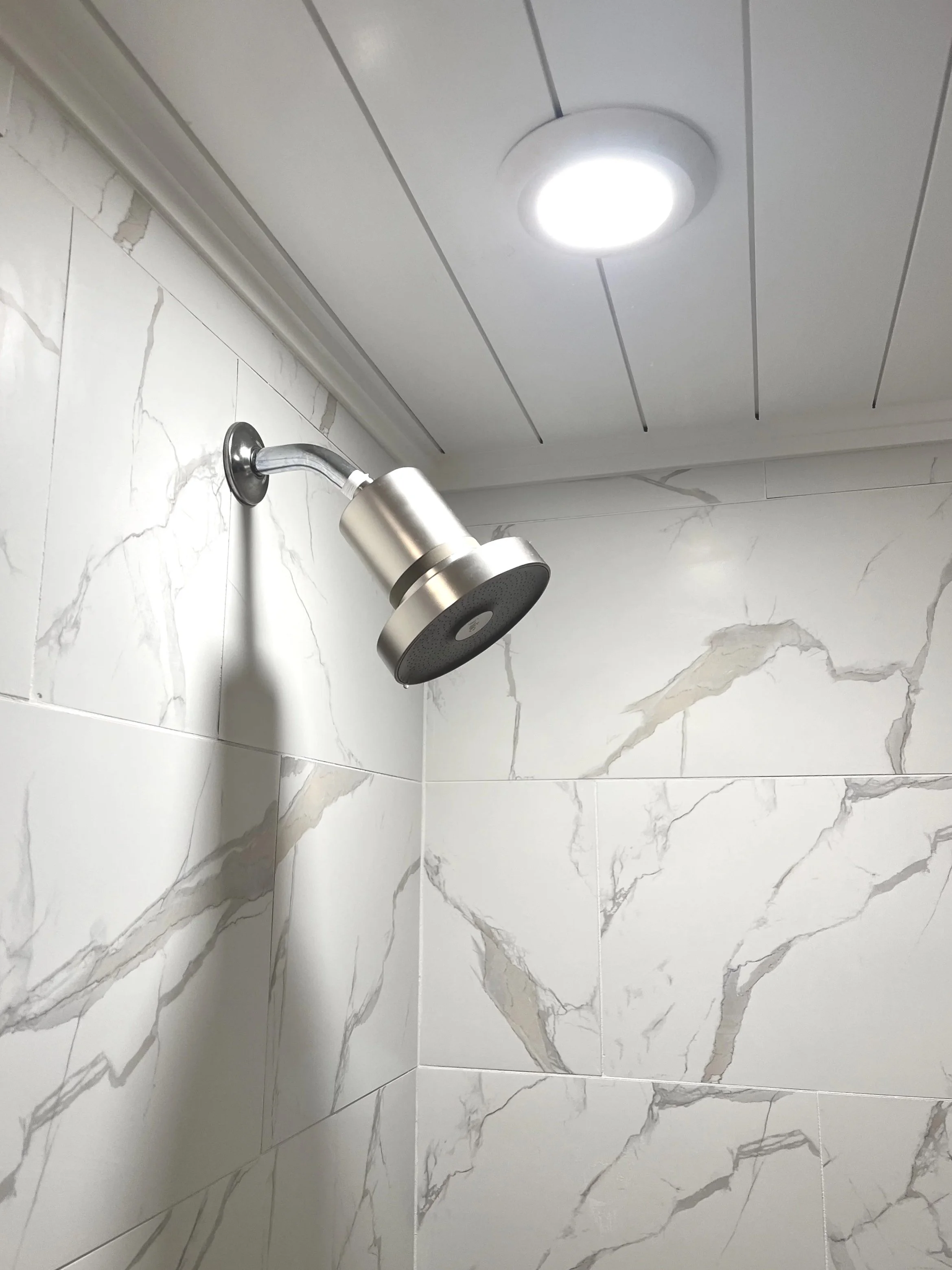 Large-format porcelain shower tile with white shiplap ceiling and LED lighting in a custom Portland bathroom remodel.