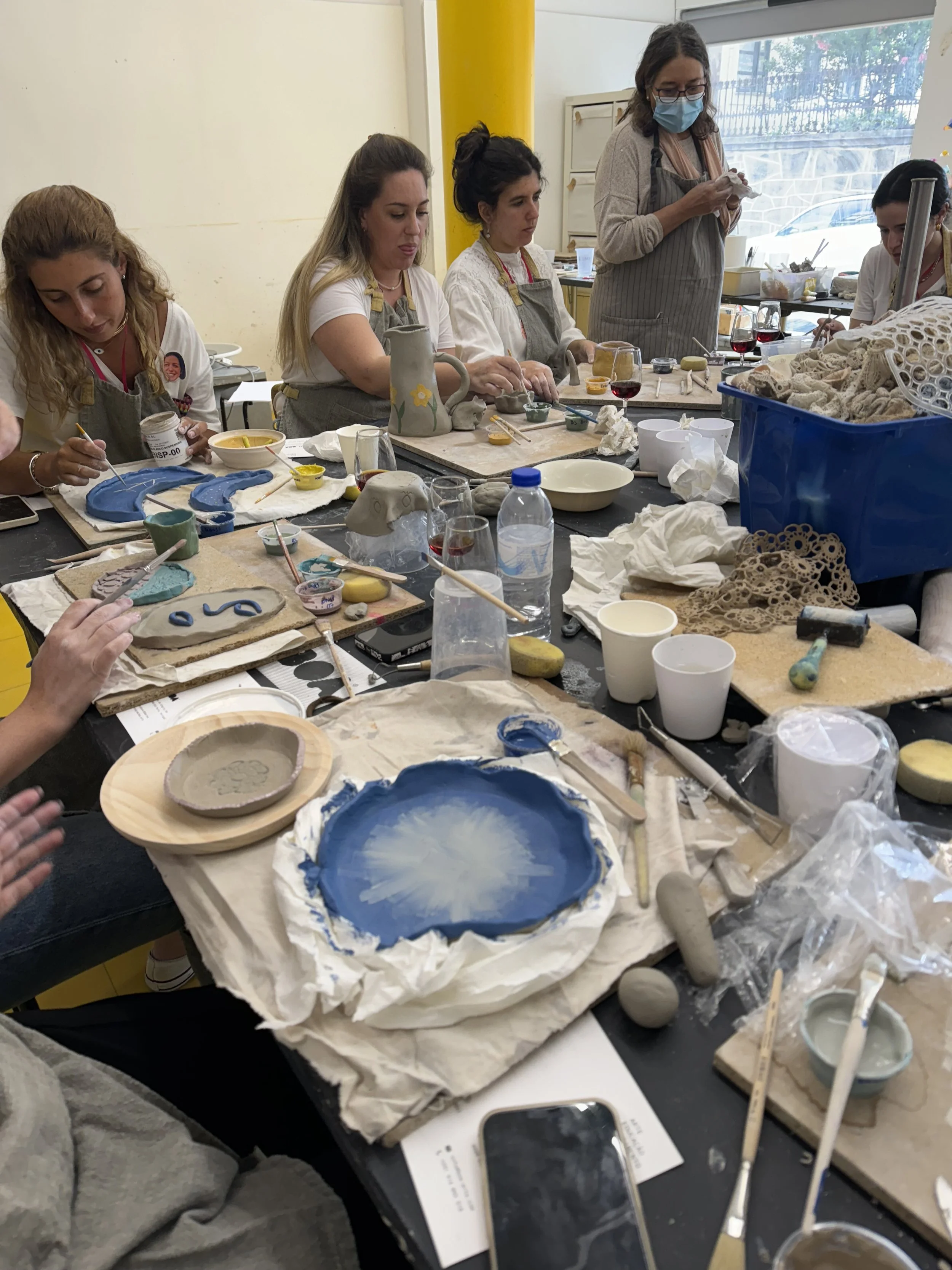 Grupo de pessoas participando de uma aula de escultura em argila, trabalhado com diversas cores e técnicas, em um ambiente bem iluminado