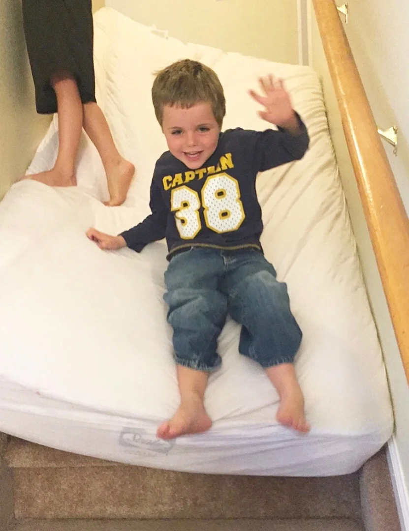Beckett and Caleb slide down stairs on mattress