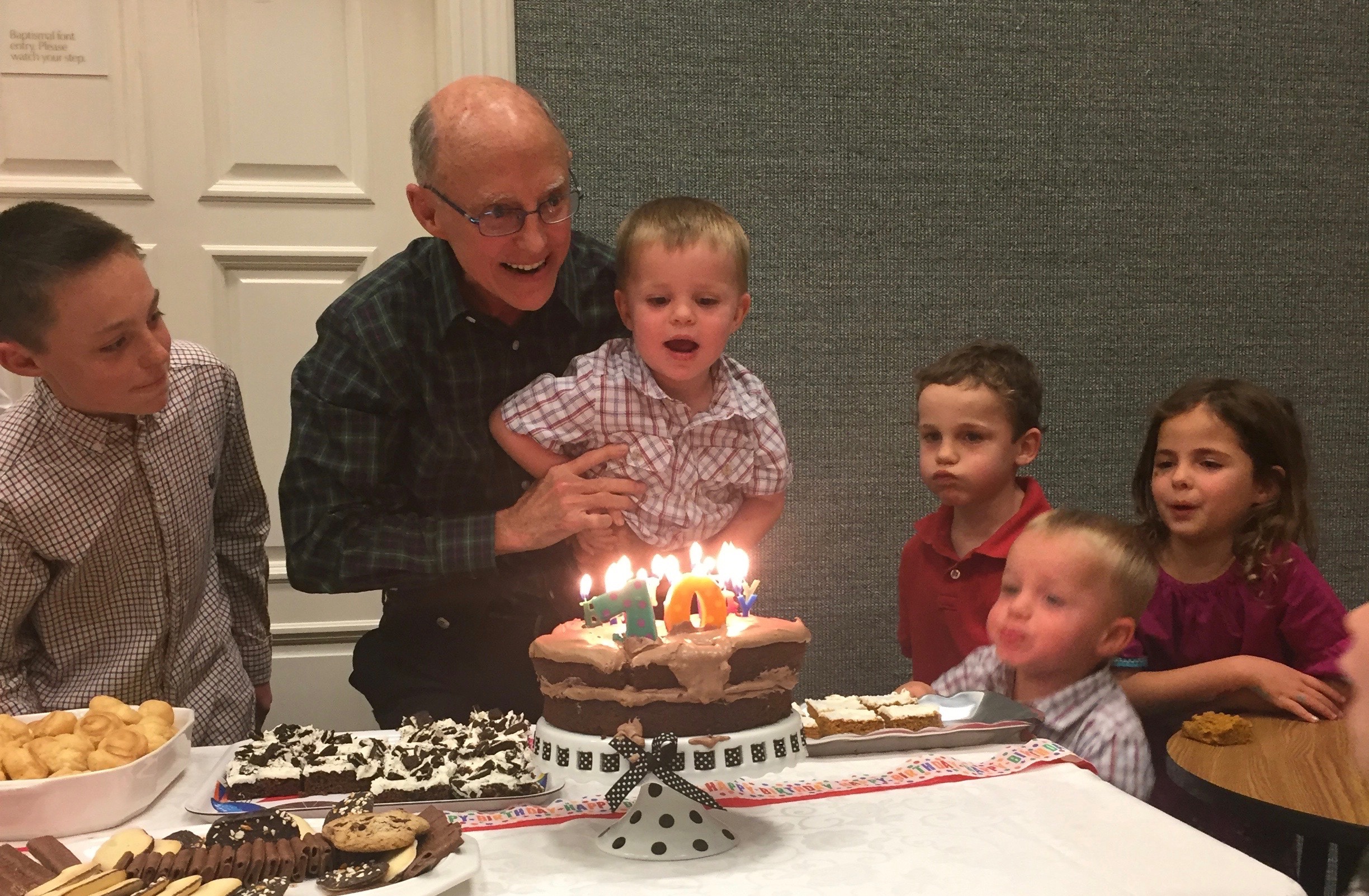 Several grands help Fred blow out the candles.