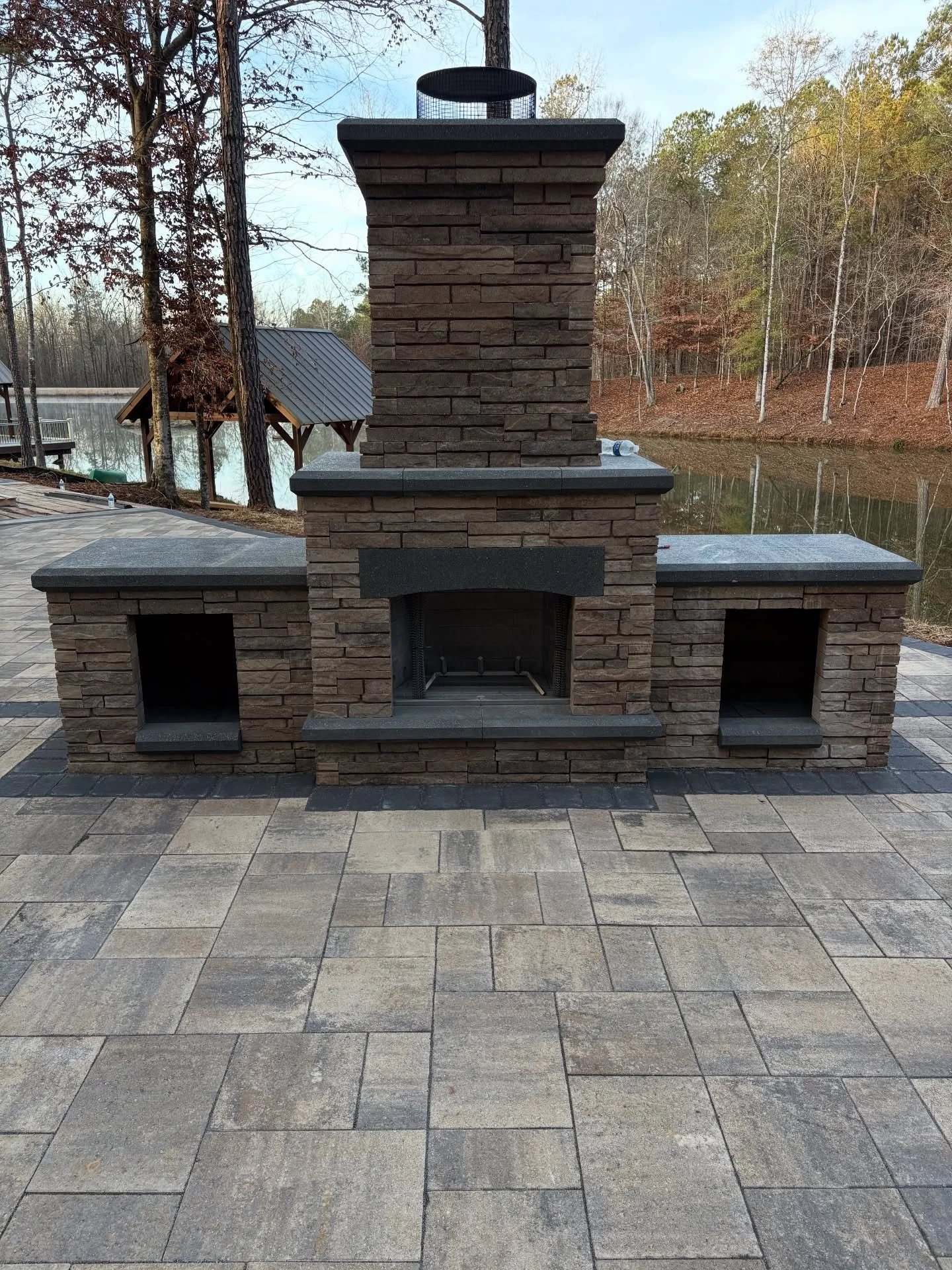 Fireside views and lakeside lounging.
🔥 
The Belgard Bordeaux Series Fireplace is a great compliment to this lakeside lounging area. We used Belgard Origins 12 for the field pavers with a Belgard Cambridge Cobble solider course. The Diamond Pro wall