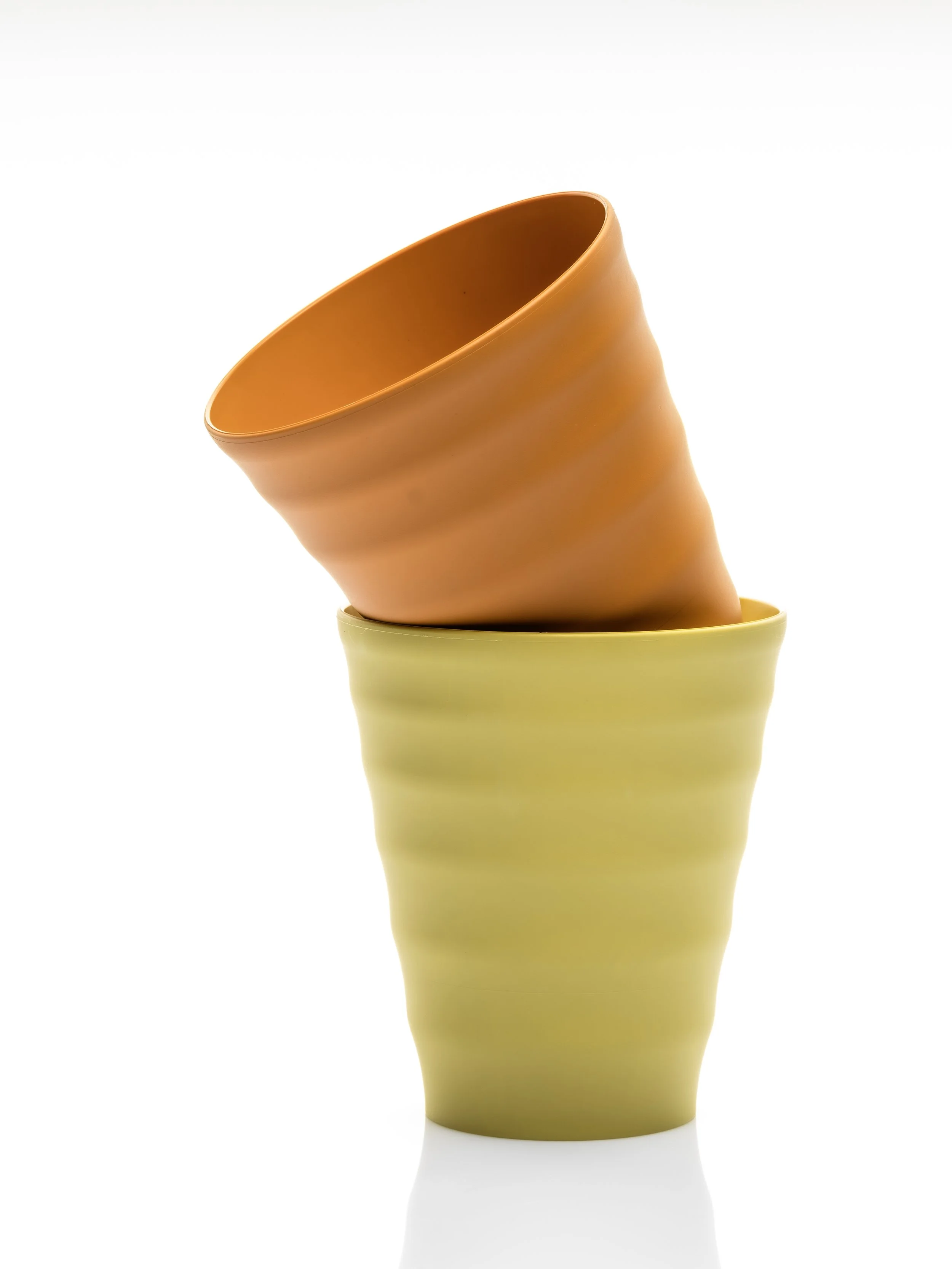 A stack of three ceramic vases in shades of yellow, orange, and brown, with the orange vase positioned at an angle on top of the yellow and brown vases, against a plain white background.
