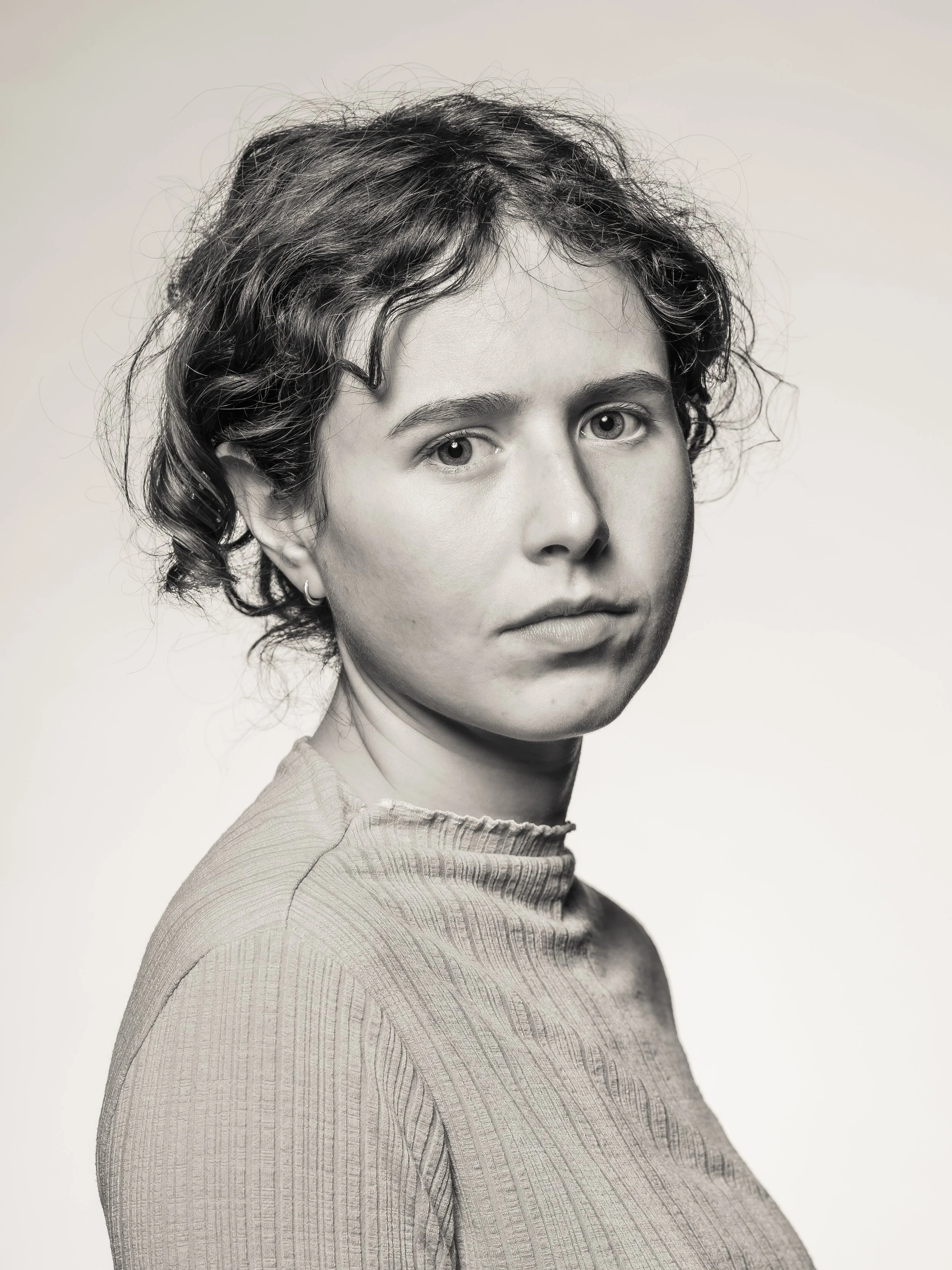 Black and white portrait of a woman with short, curly hair wearing a textured top and small hoop earring.