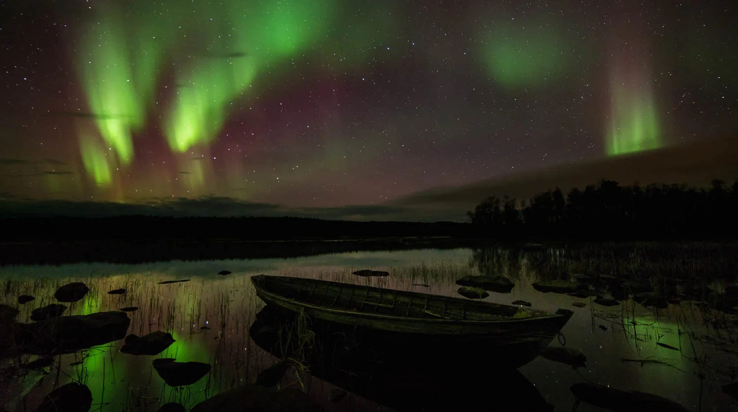 Puuvene Juutuanjoessa revontulten alla.