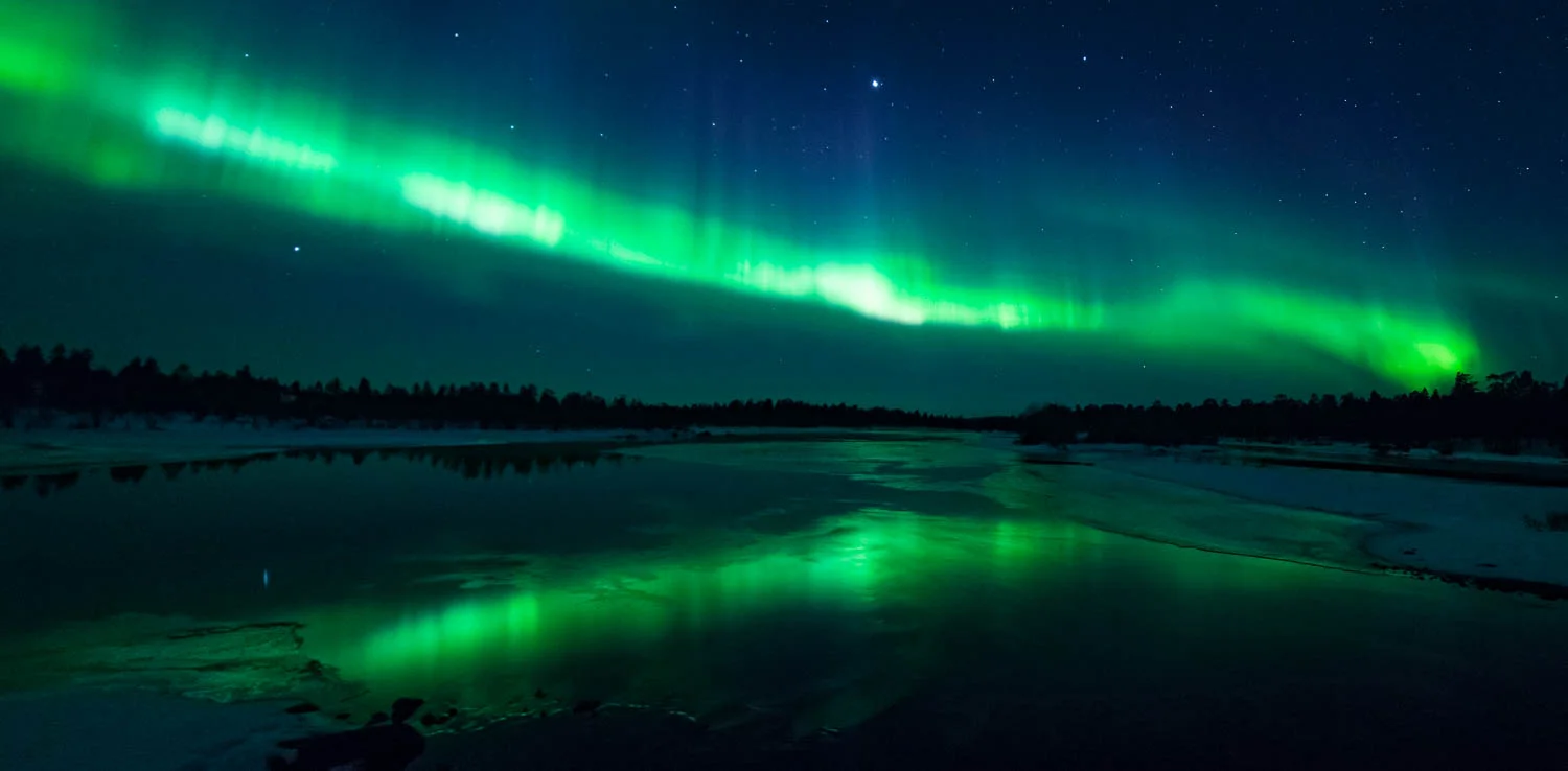 Revontulikaari heijastuu joesta.