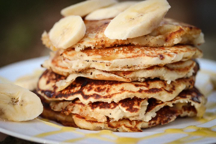 Fluffy Vegan Banana Pancakes Prep Time: 5 mins Cook Time: 2 mins Level: Easy - Easy Makes: Pancakes for 2 Ingredients: · 200 ml plain white flour (measure it in a measuring jug) · 300 ml of oat milk or dairy free milk (almond, soya, coconut) · 2 tbl spoons baking powder · 1 tbl spoon of Fairtrade organic sugar · Pinch of salt · 2 tbl spoons of Coconut Oil · 1 fairly ripe Banana Method 1. Measure out all your ingredients. 2. Preheat non-stick pan to a medium temperature 3. In a large mixing bowl, combine oil the dry ingredients together along with the oil – mix well 4. Next add the milk in a slow steady stream whilst whisking 5. Whisk thoroughly until you have a smooth fairly thick texture (If there are little lumps in it don’t worry, it is just the coconut oil and will melt during the frying process. 6. Ladle pancake mixture onto the pan and cook for around 1.5 minutes. You want the pancakes to be brown and bubbling. 7. Whilst the pancakes are cooking add some of the sliced bananas into the pancakes and then flip. 8. Cook for another 1.5 minutes or until golden brown. 9. Remove from pan and stack’em up! 10. Garnish with plenty of syrup and bananas. 11. Enjoy the most delicious, fluffy pancakes!