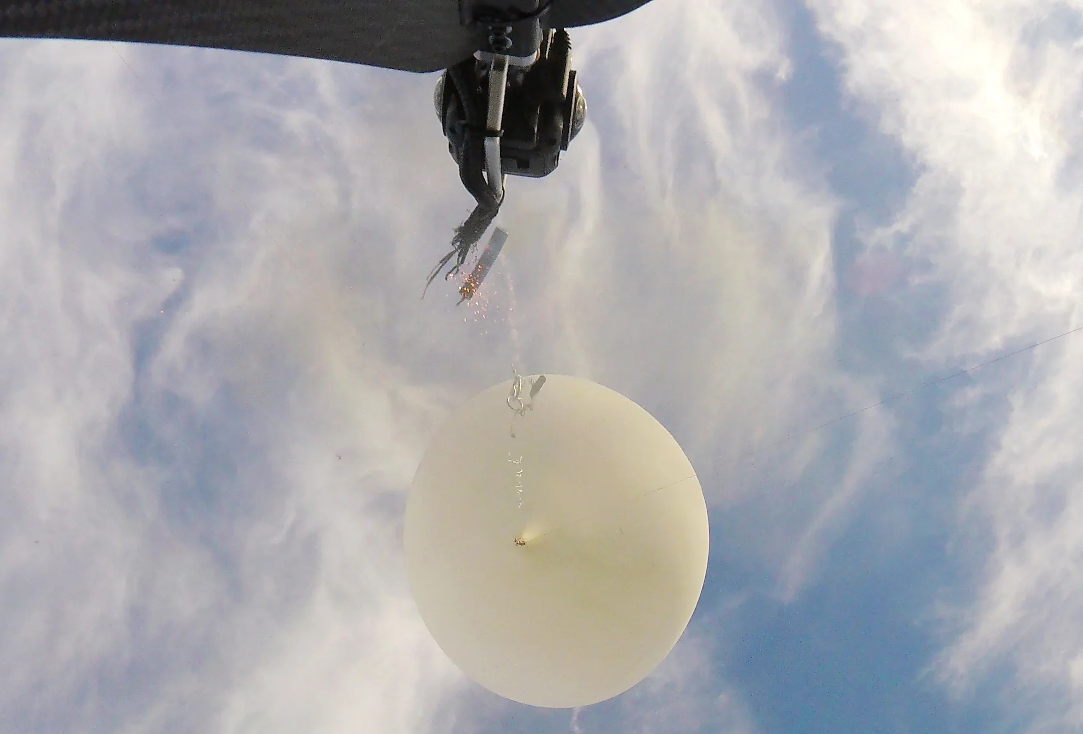Secondary camera view of the cutdown pyro at the moment of firing. The main tether is already recoiling upward like a spring. The primary 360 camera is visible at top center.