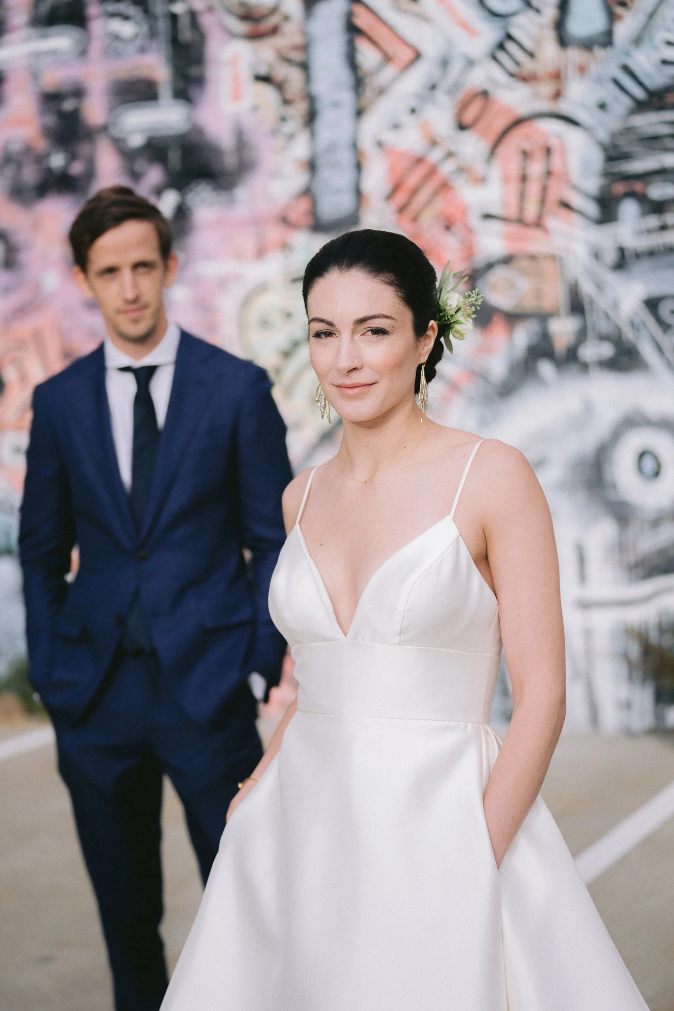 fine art portrait wedding photo in front of graffiti wall in san francisco - bride is in focus and groom is blurred out in the background.