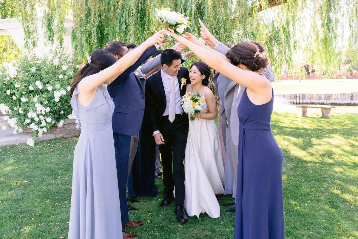 Wedding Party making tunnel for bride and groom in front of weeping willow tree at San Ramon Waters by Wedgewood weddings