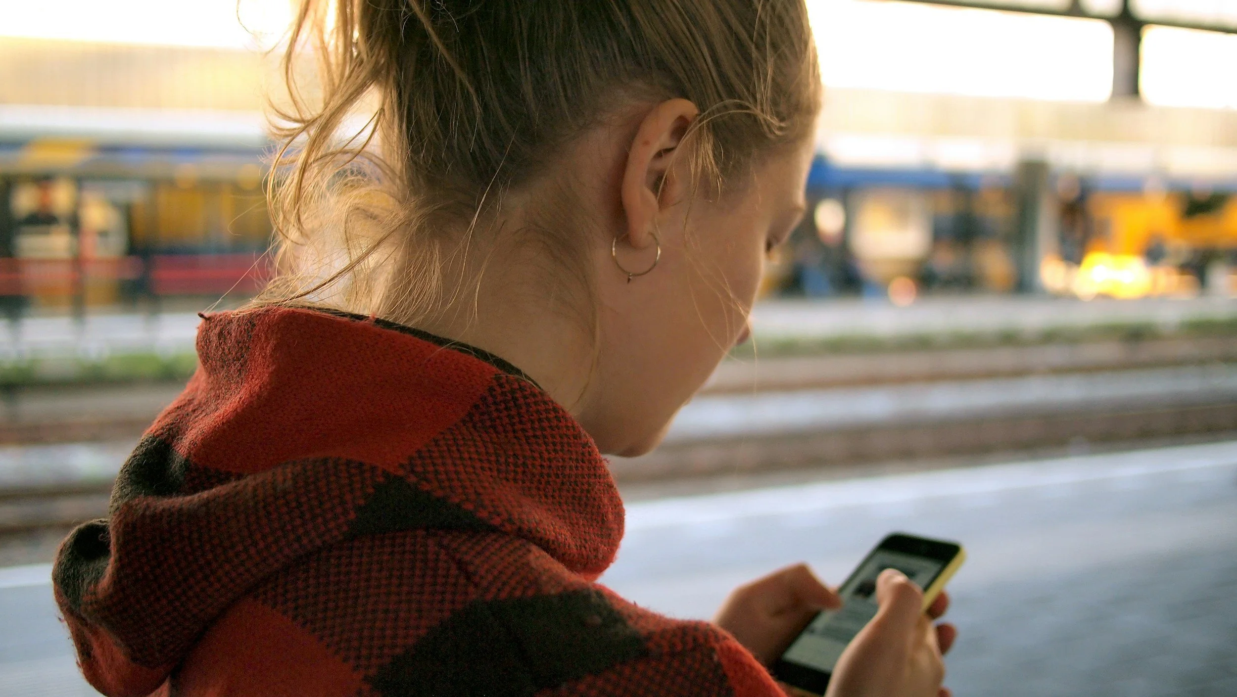 Person looking down at a smartphone with the neck flexed forward, illustrating phone-related neck strain and poor posture.