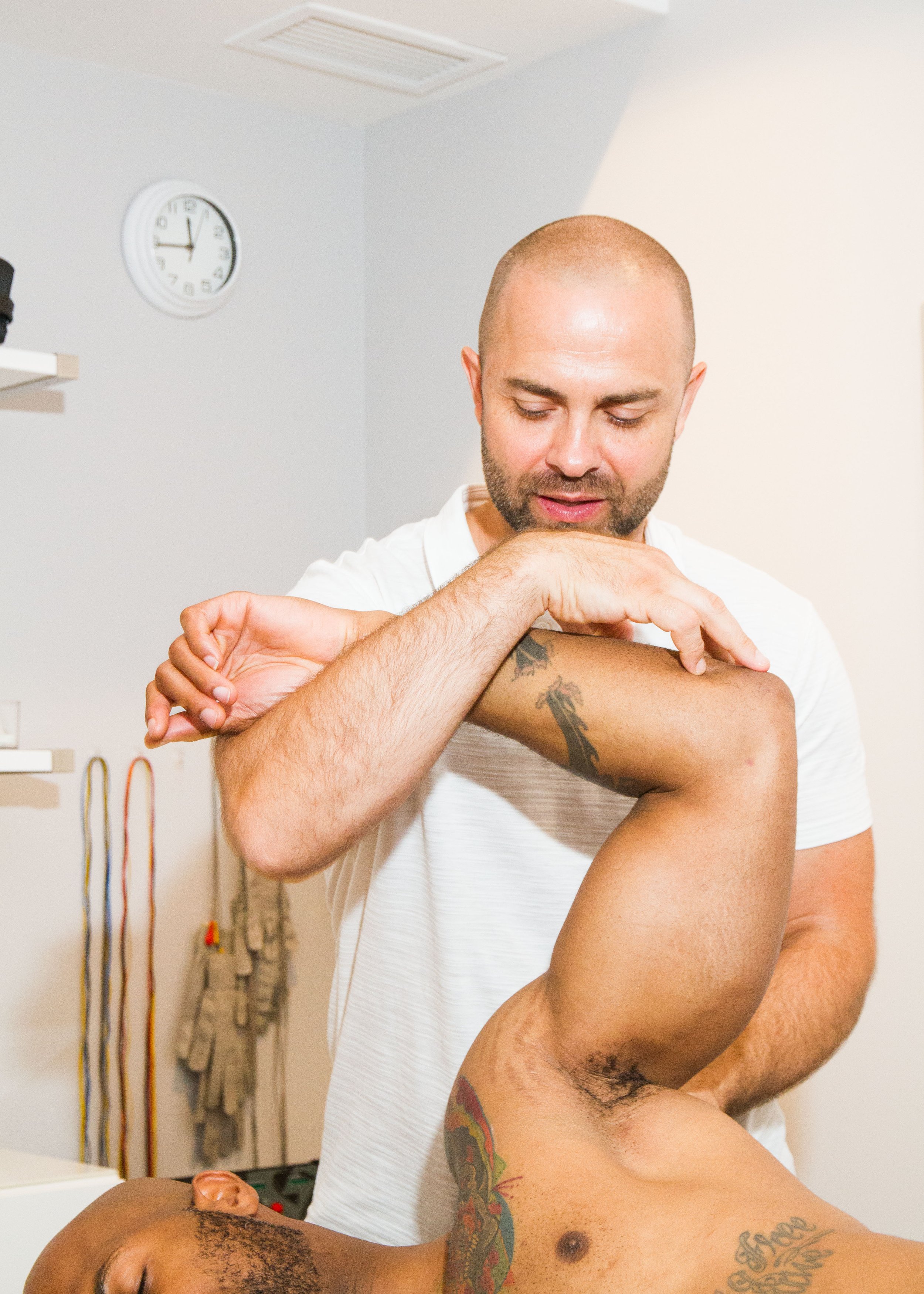 Chiropractor performing a shoulder mobility assessment with a patient during a treatment session at ONE80 Health.