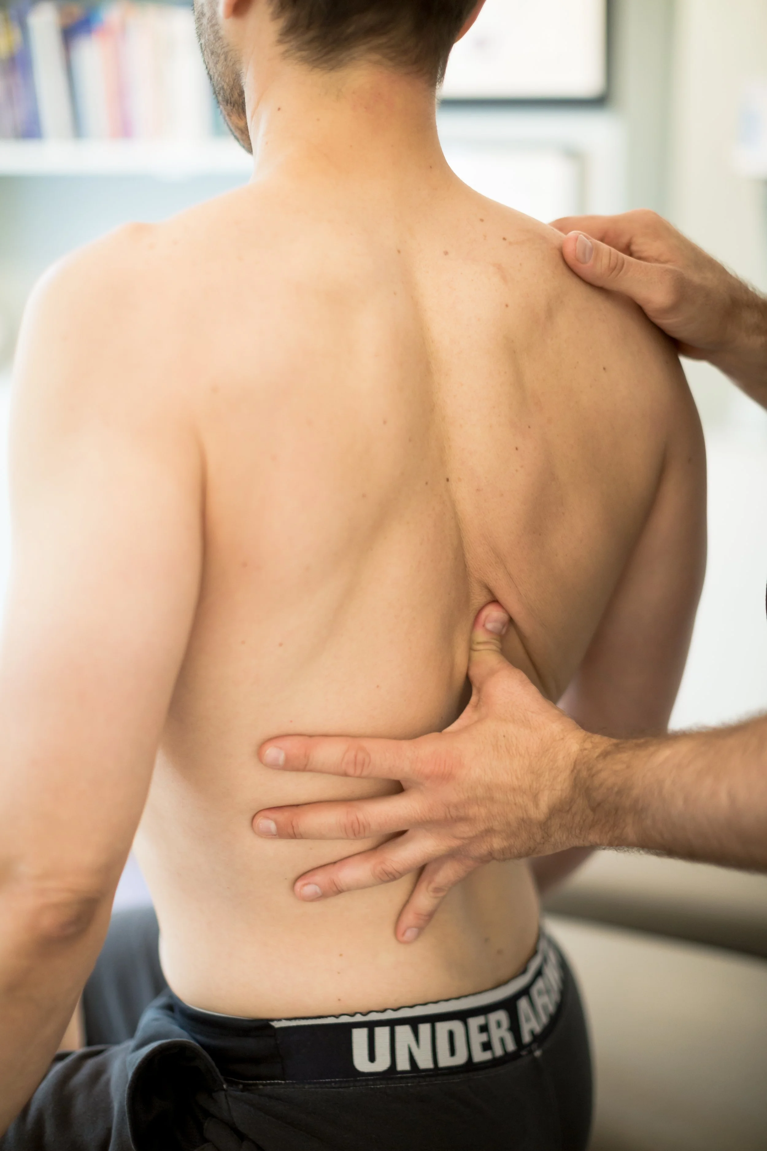 Practitioner assessing posture and movement patterns during an osteopathic evaluation