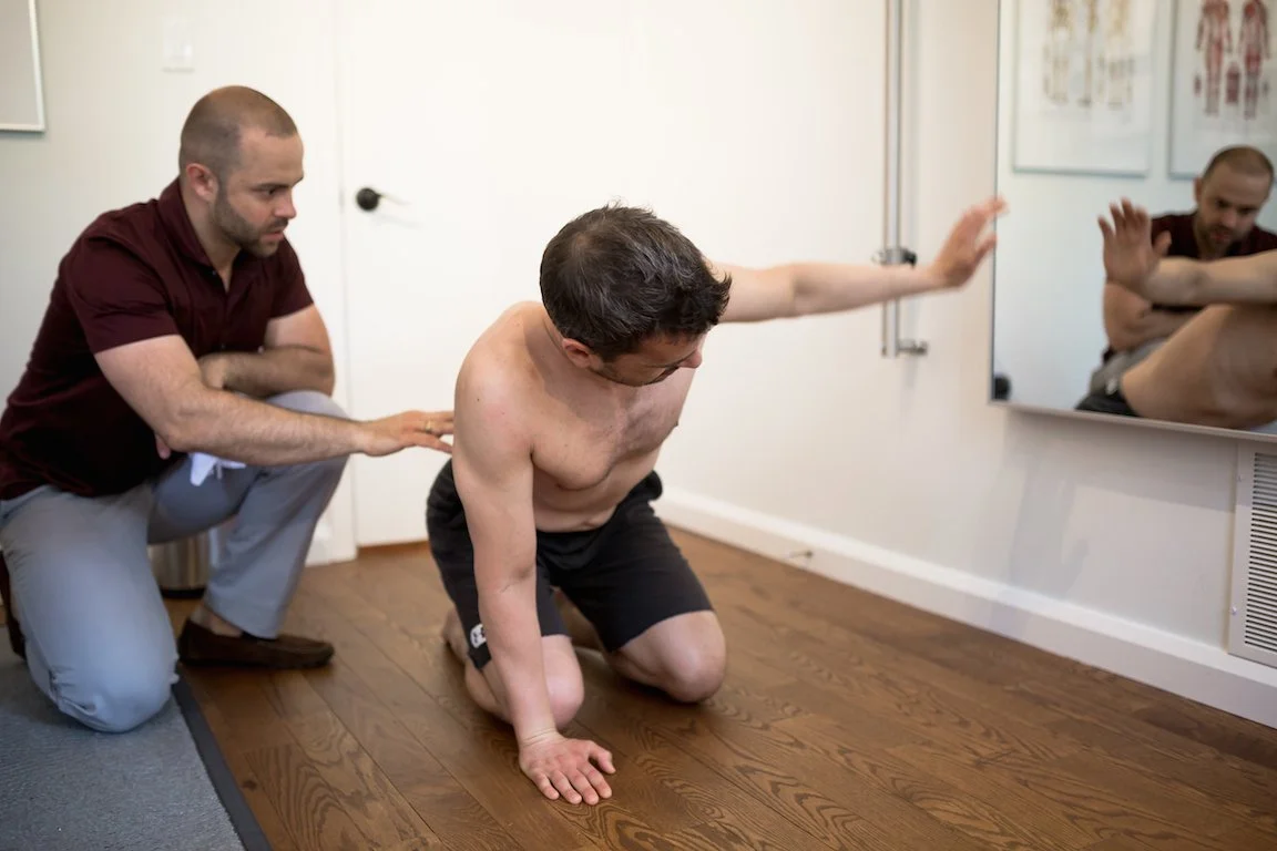 Chiropractor assessing shoulder and scapular stability in a patient during a clinical examination at ONE80 Health in Toronto