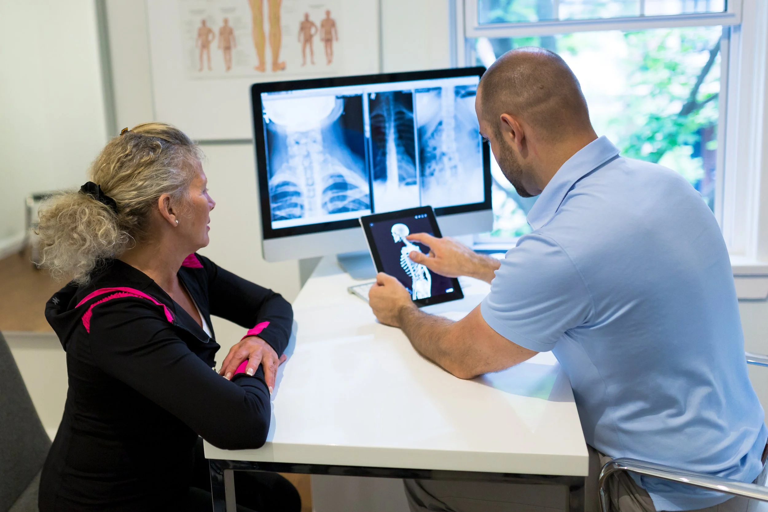 Chiropractor discussing assessment findings and movement-related factors during a consultation at ONE80 Health in Toronto.