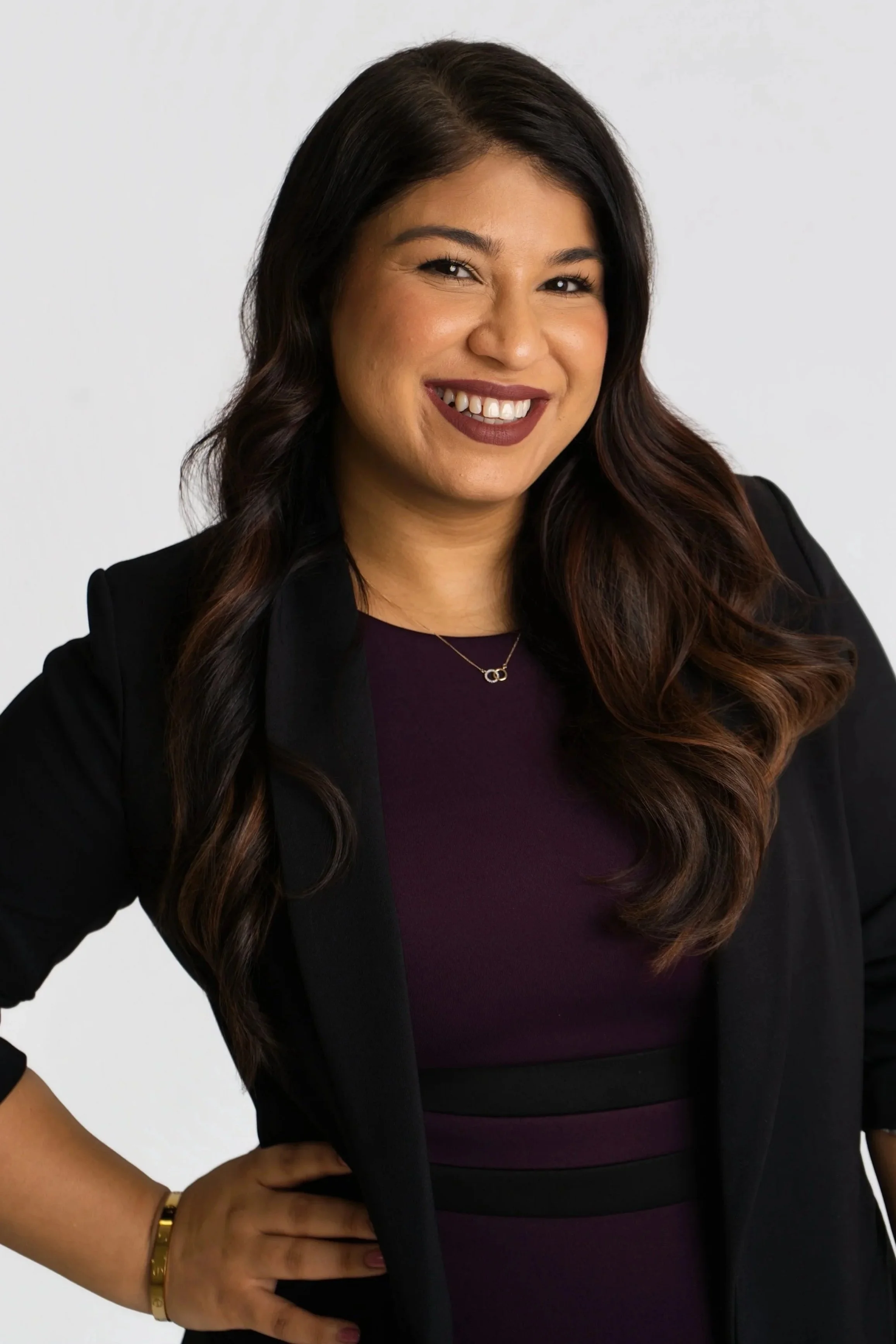 A professional woman with straight black hair, light makeup, wearing a blue blazer and black shirt, smiling confidently at the camera.