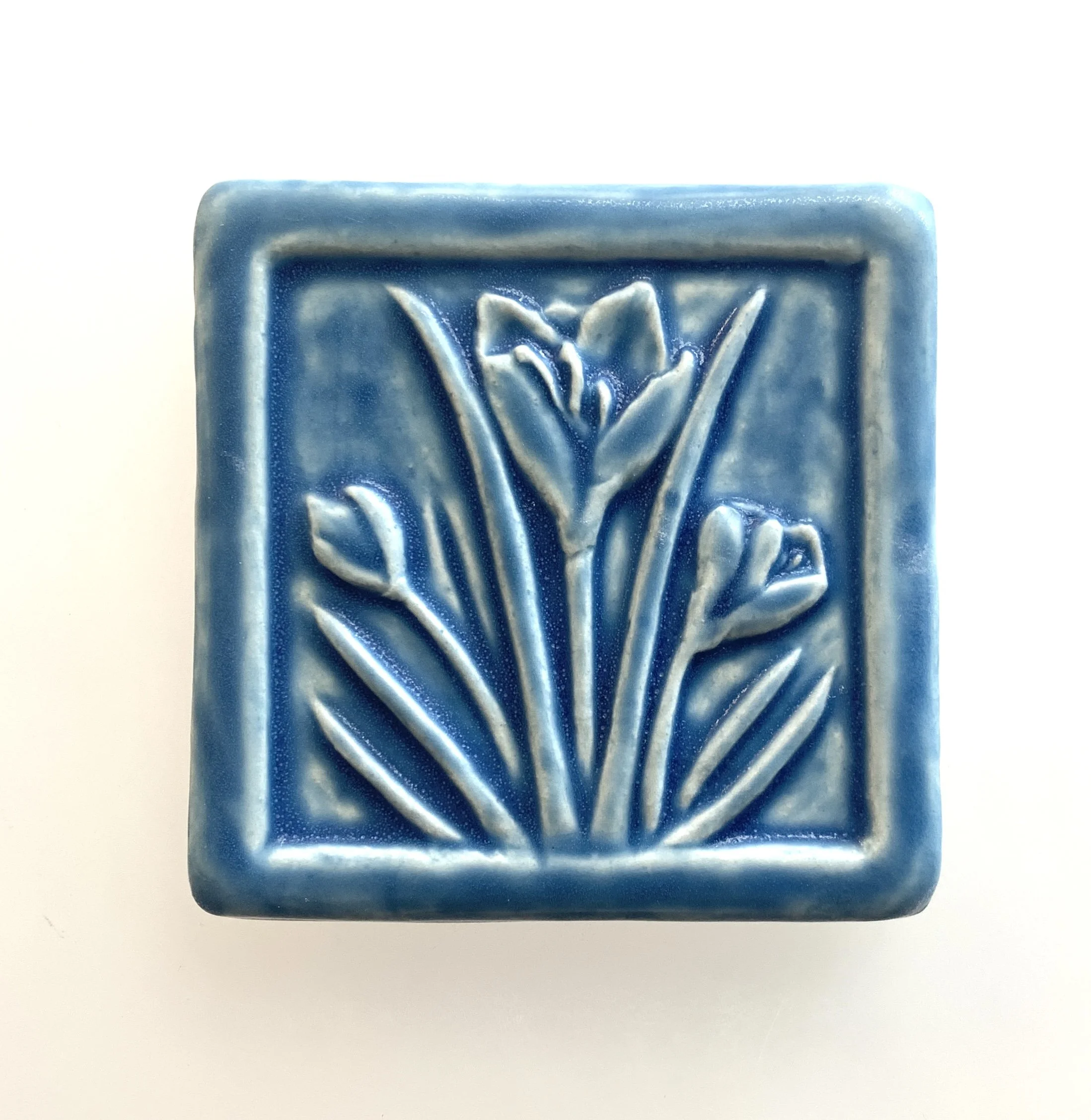 Handcrafted 4x4 inch Whistling Frog Crocus art tile in a matte glaze, featuring a raised crocus flower design, suitable for gifting, or tile installation in kitchen, bathroom, or fireplace.