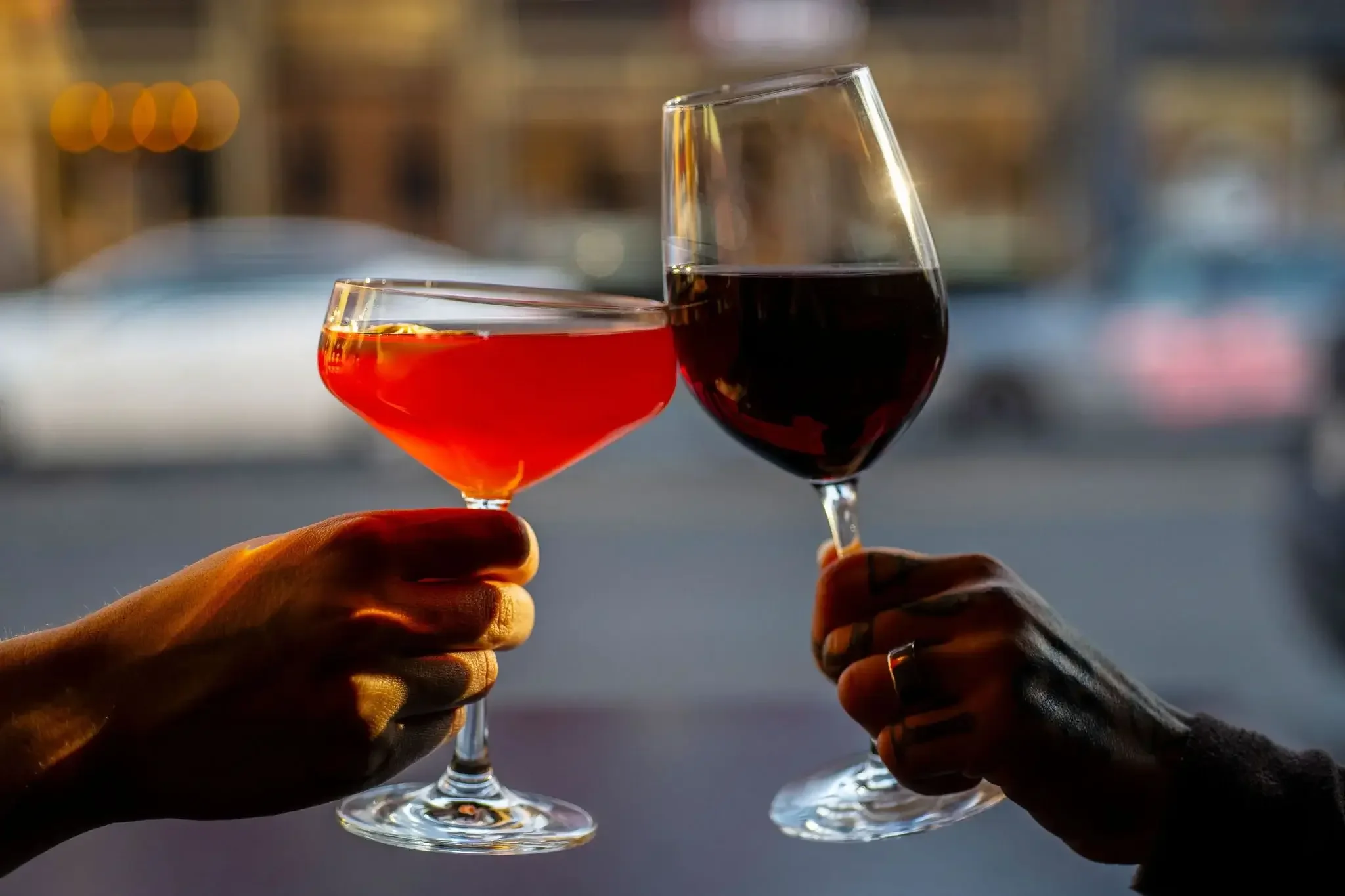  Two people cheers their drinks at the Dutch Ale House in the Hudson Valley, NY. A red gimlet-style drink, and a glass of red wine. 
