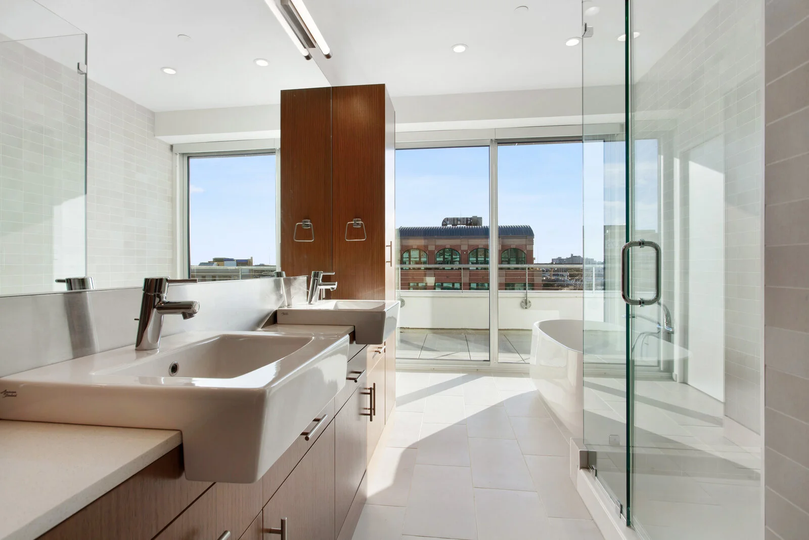  Luxury Apartments for Rent in New Orleans LA - The Garage - Spacious Bathroom with Wooden Cabinetry, Large Windows, Glass Shower, Dual Sink, Large Mirror, Tub, and Balcony 