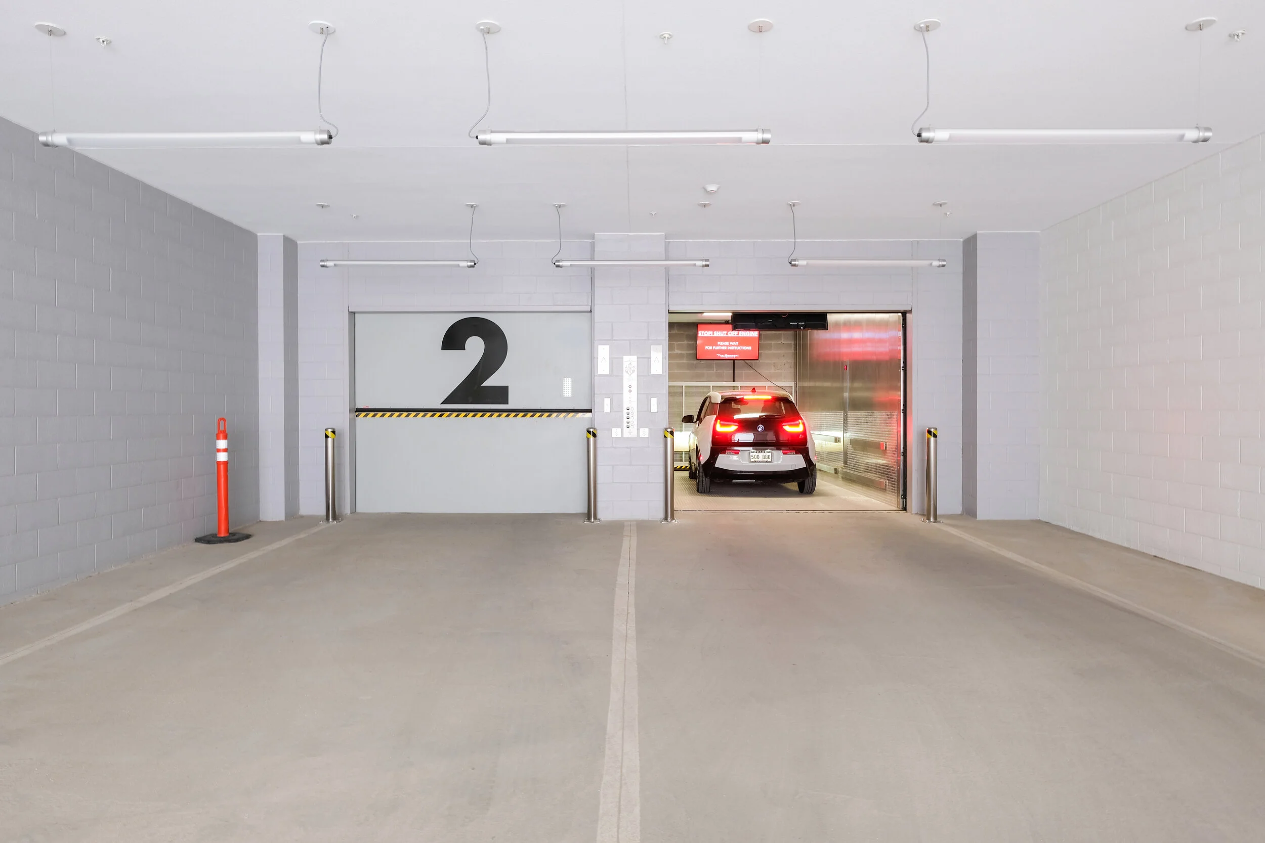 Luxury New Orleans, LA Apartments - The Garage - Garage Elevator With Vehicle, Multiple Lighting Fixtures, and Heavy Duty Safety Bollards. 
