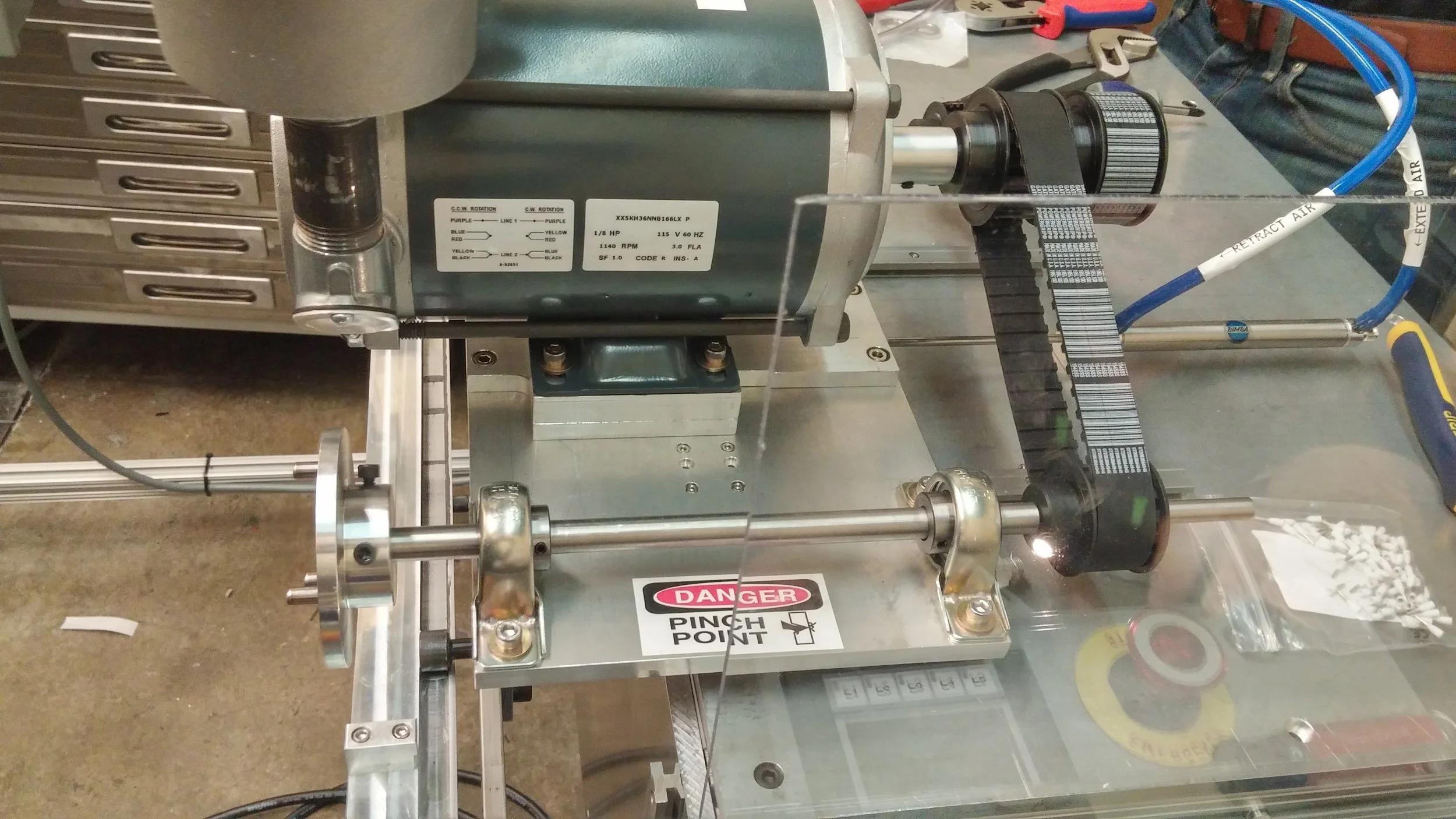 (Above) Driven by a belt drive, three pronged keys on the shafts to engage with rollers. The drive sits on linear rails with a linear actuator to engage with the rollers (Left) Adhesive spray gun attached to adhesive delivery and pneumatic actuator lines