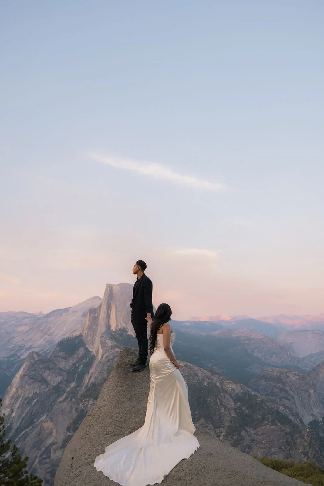 Bride and groom hold hand at the top of Glacier Point for a sunrise wedding