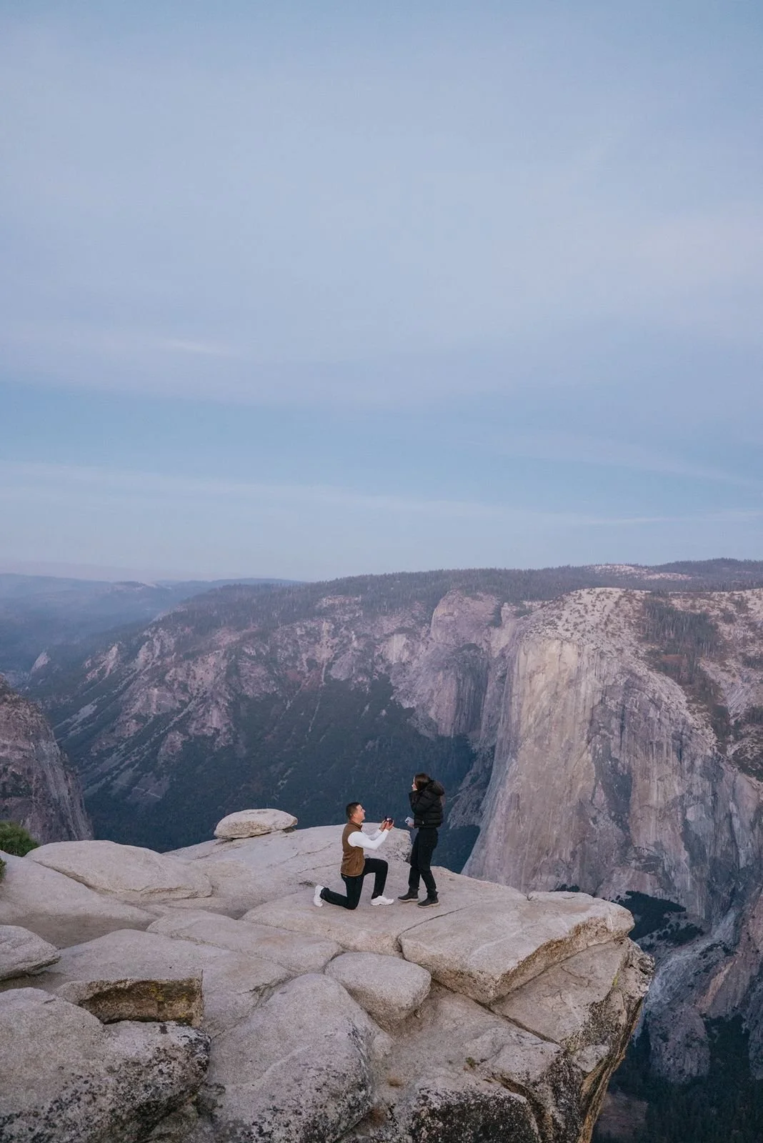 Man proposing to his fiancé at sunrise at Taft Point, Yosemite.
