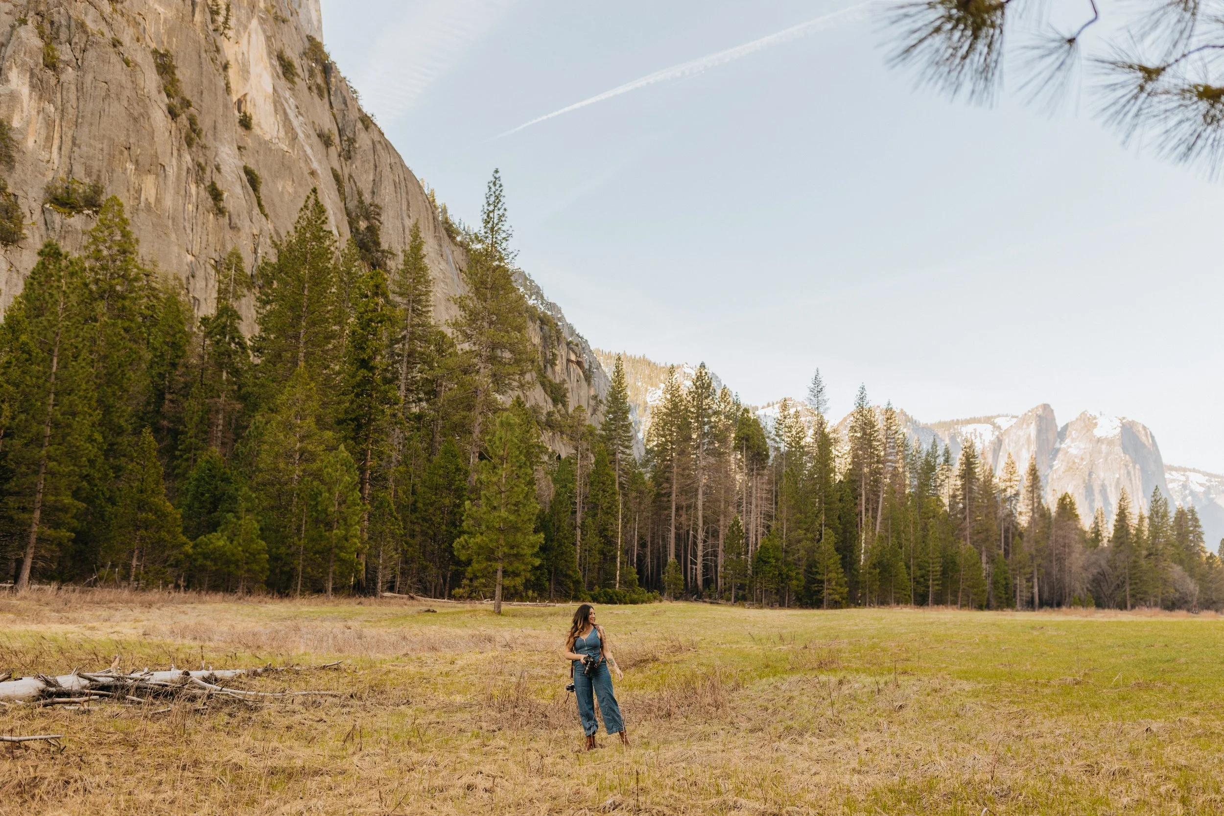 Yosemite photographer Priscilla Ban standing in a field of tall pines and snowy peaks.