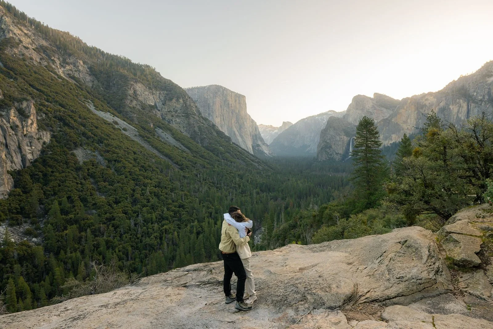 Engaged couple hugging at sunrise after a Yosemite Tunnel View marriage proposal.
