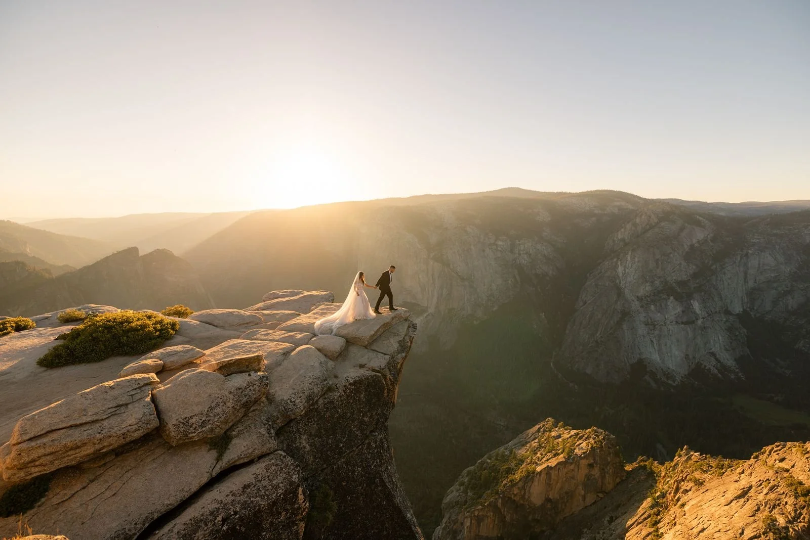 A couple stands on Taft Point at sunset, overlooking the cliffs of Yosemite National Park during their elopement ceremony.