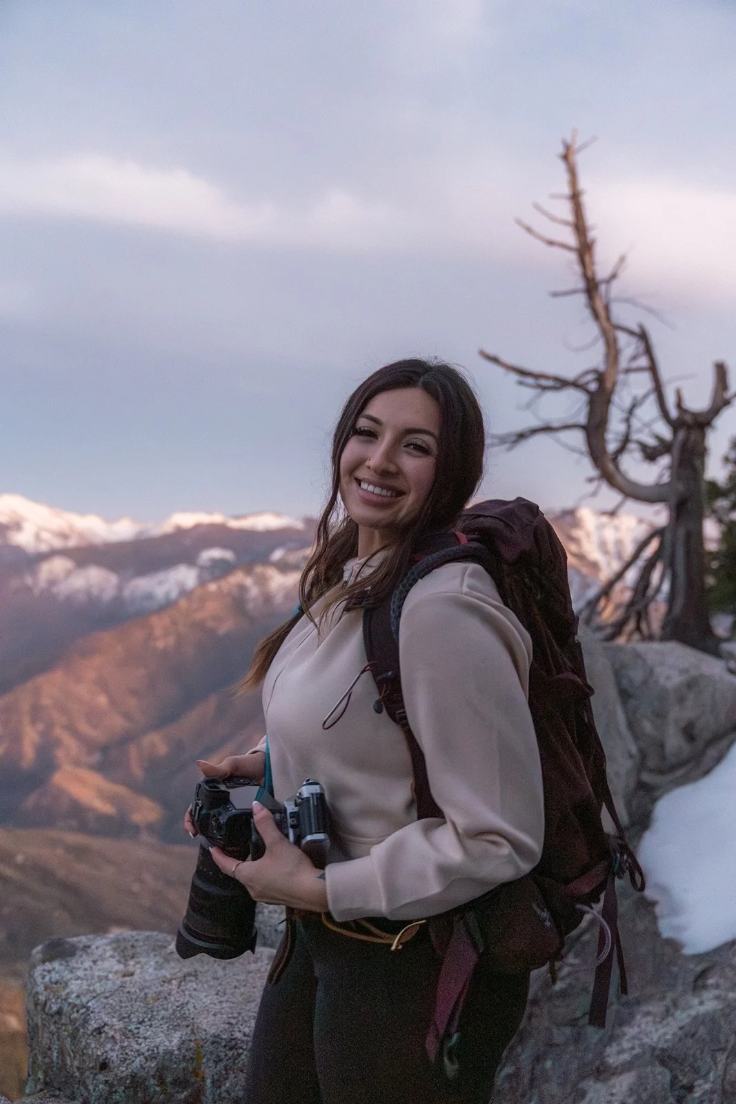 Professional Yosemite National Park photographer smiling and holding a camera with mountain scenery.