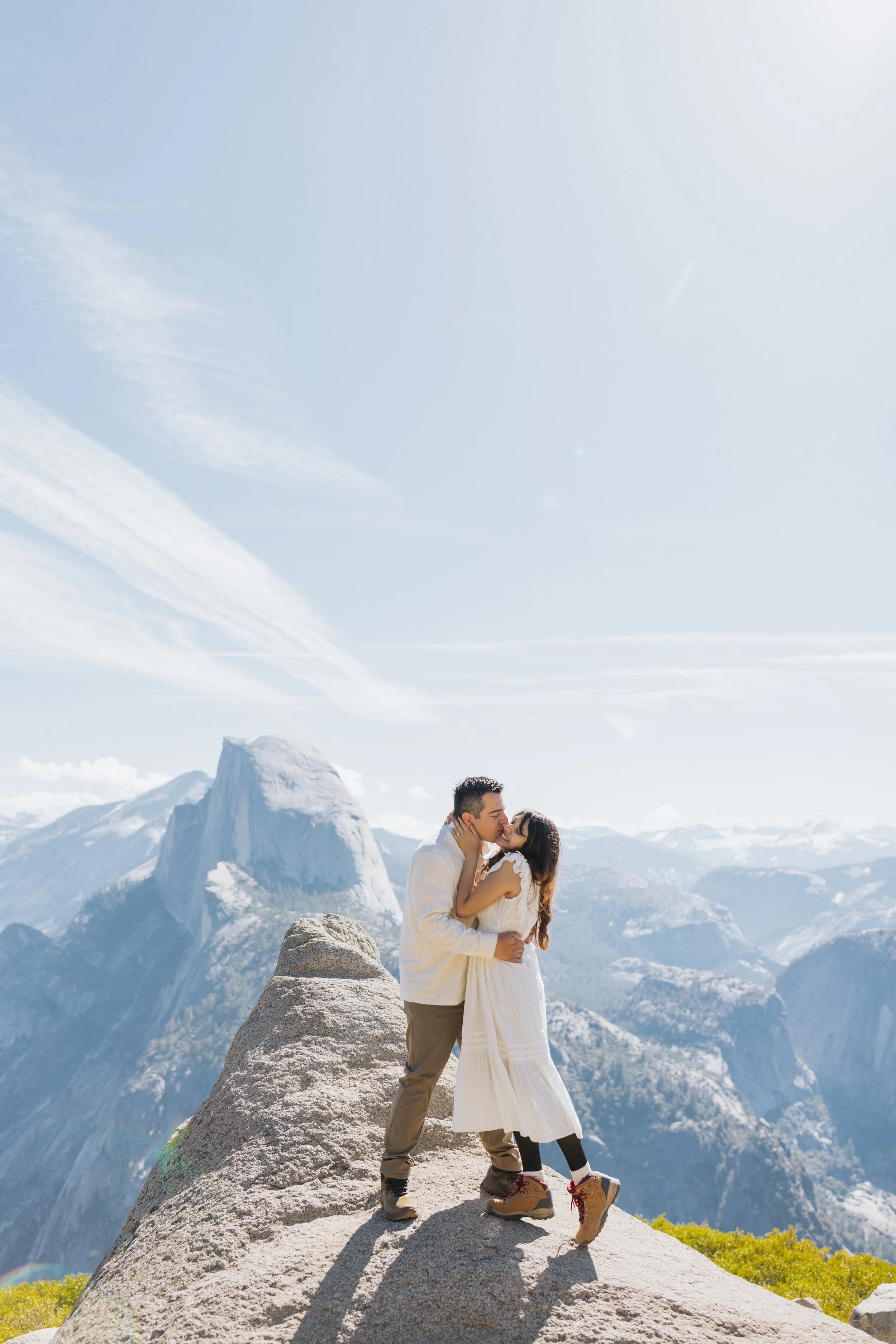 Couple kissing on a mountain ledge at Glacier Point, Yosemite National Park, photographed professionally.