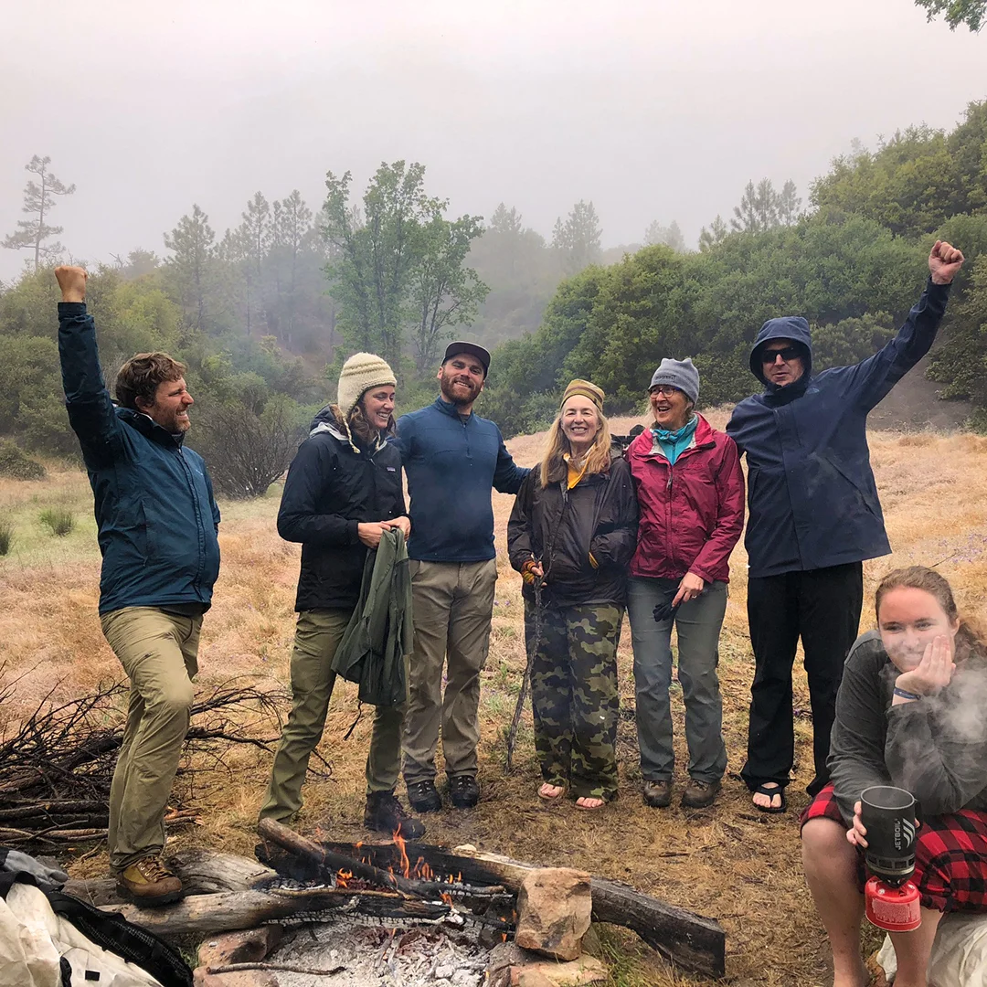 Finding joy, intimacy and community in the difficult task of making a fire after a long night of rain.
