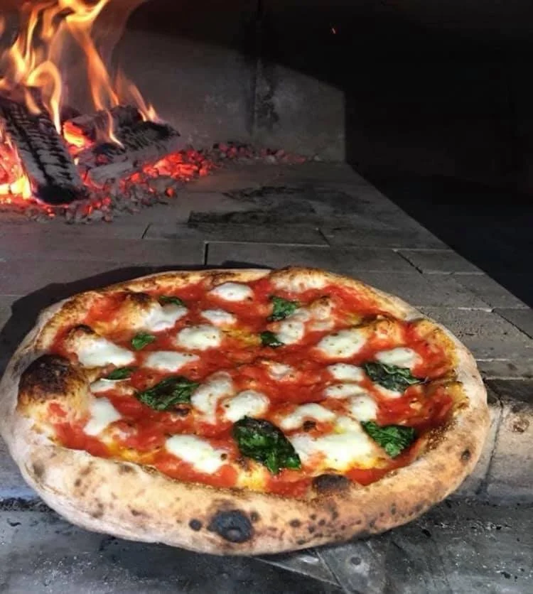 Margherita pizza beside the wood-fired oven