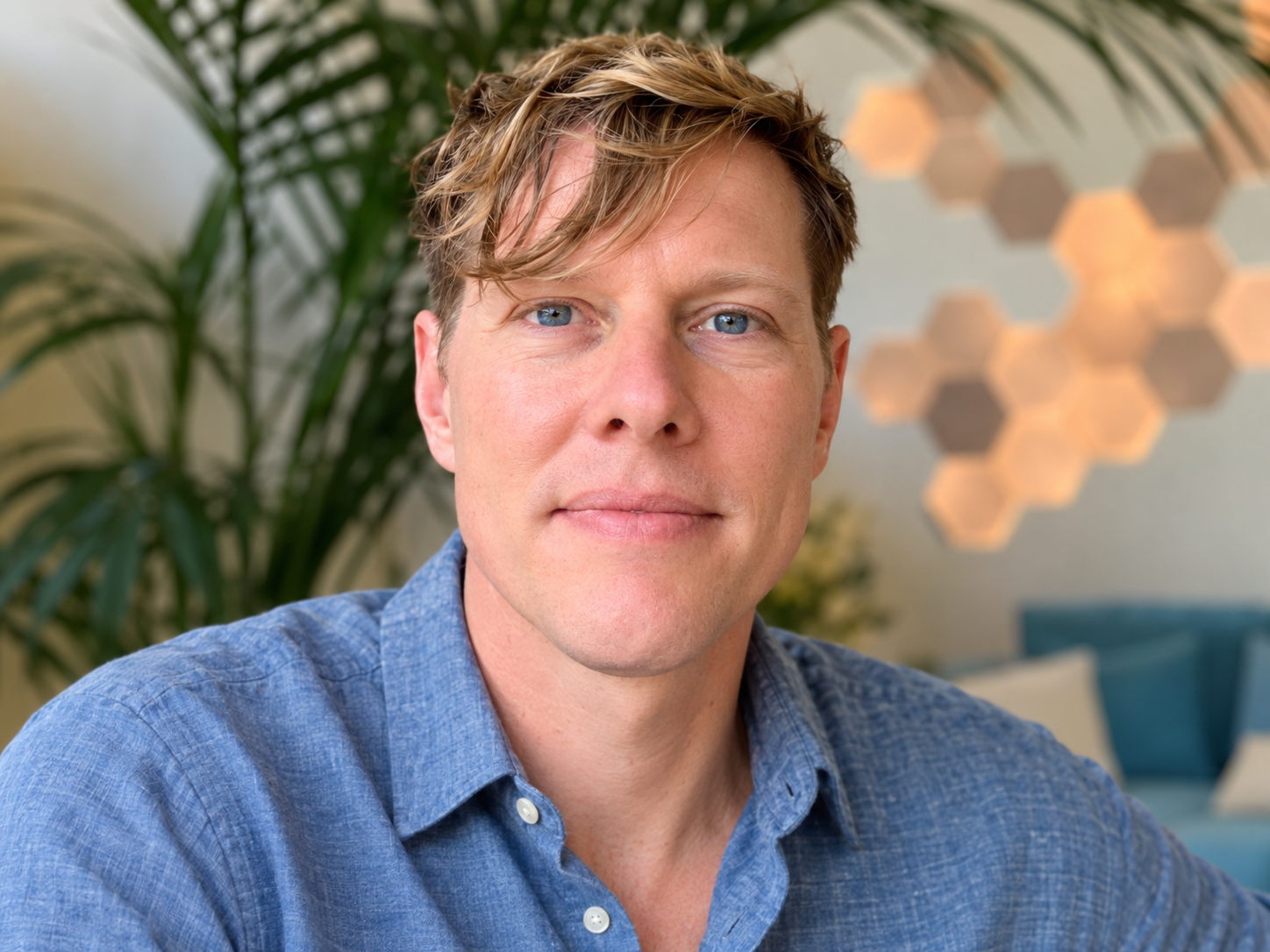 Jamie Fortin, LMFT, wearing a blue shirt, with plants and warm lighting in the background.