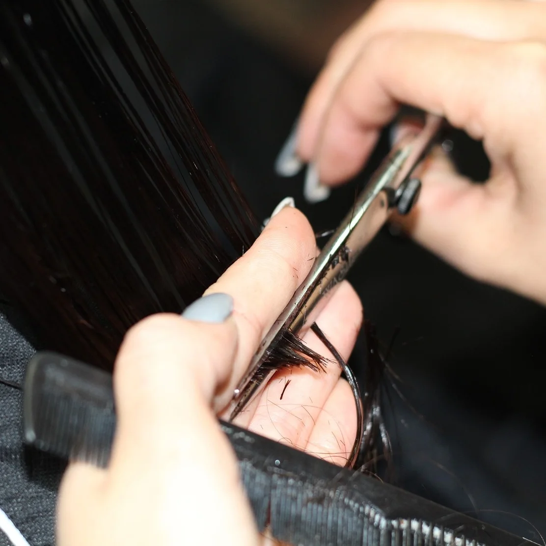 Closeup of hands cutting hair. Only a trained wig stylist should cut your synthetic wig.