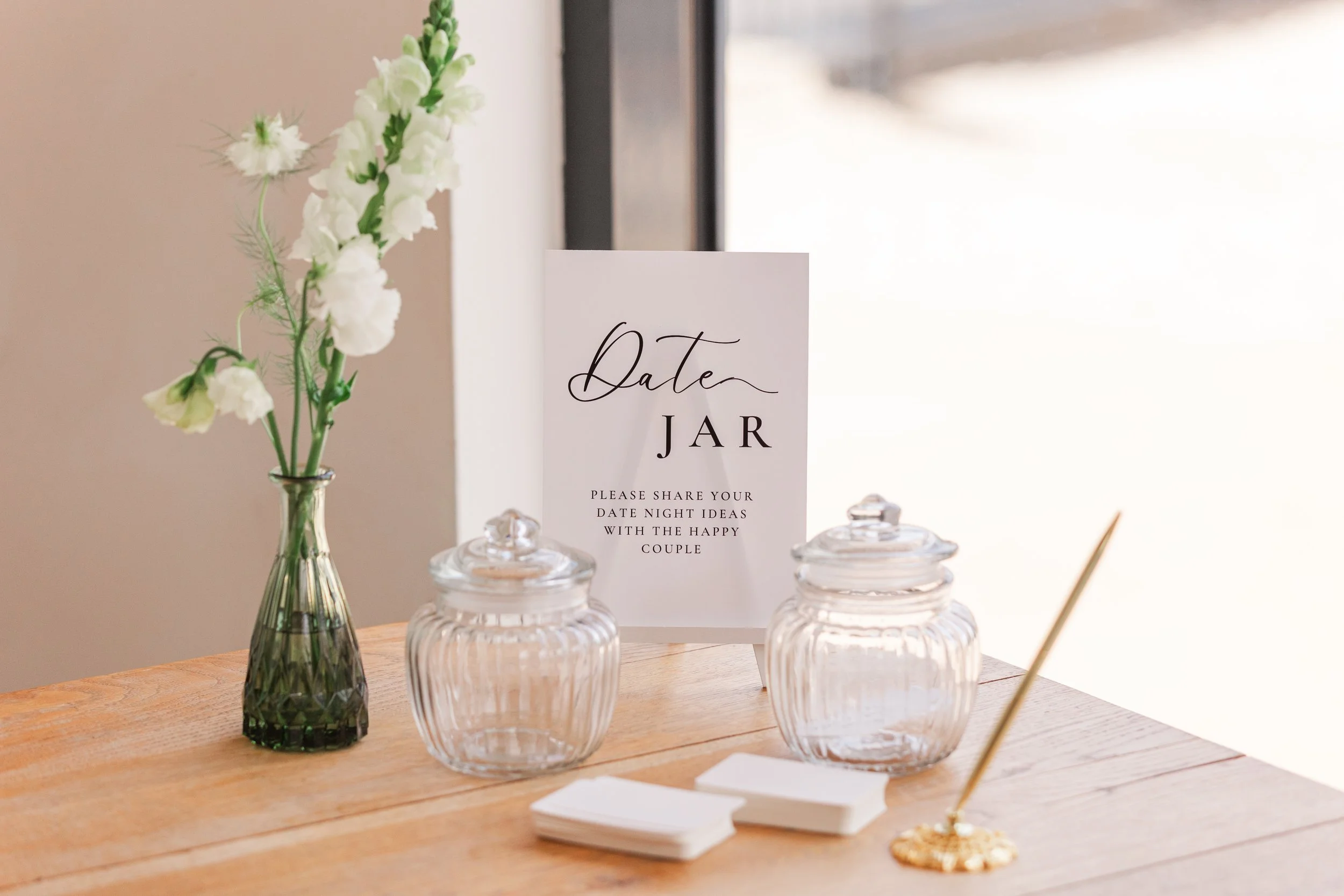 A date jar with a gold pen on a wooden table at a wedding reception